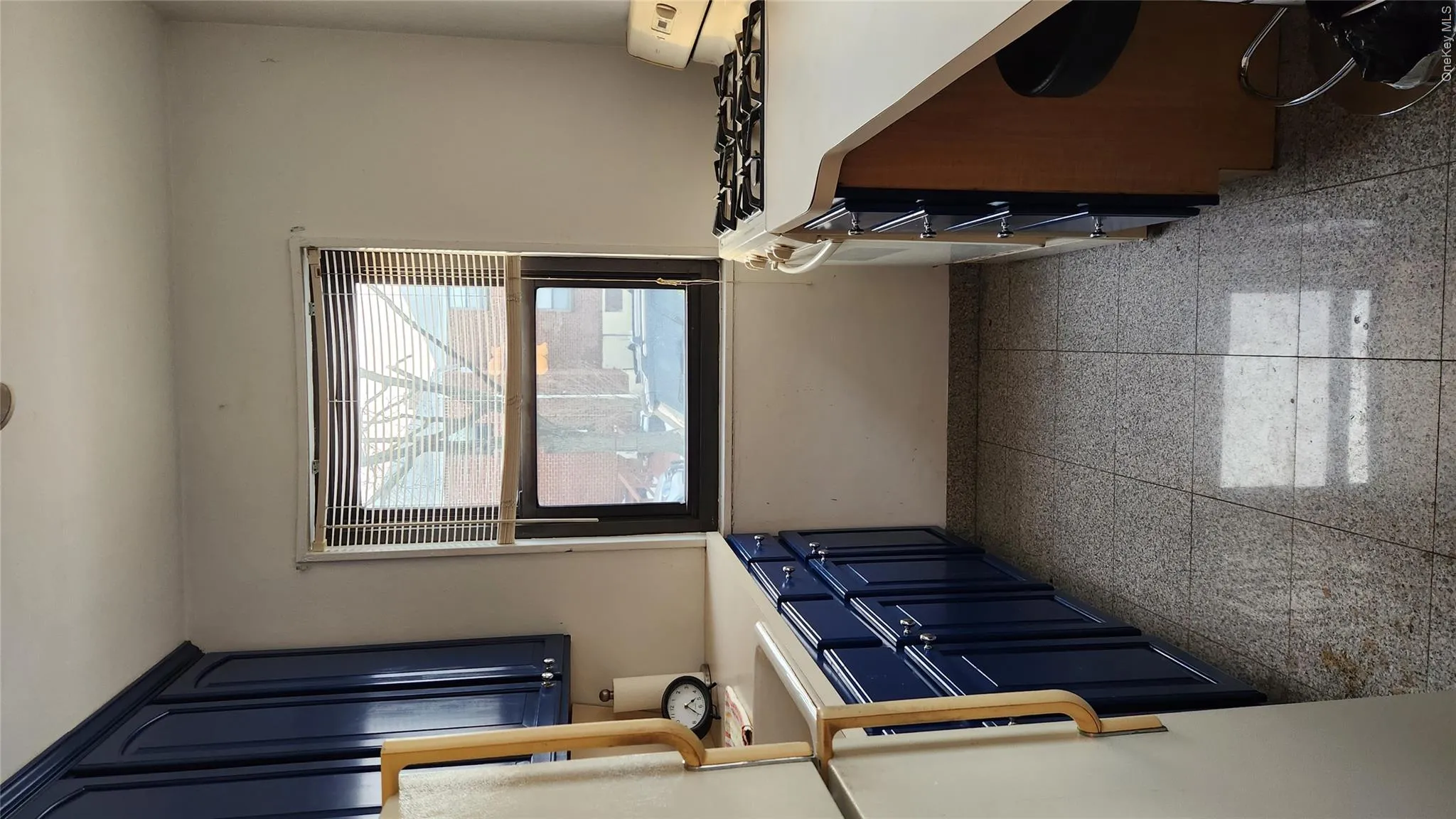 Kitchen with blue cabinets, light countertops, stove, fridge, and dark speckled floor Kitchen with blue cabinets, light countertops, stove, fridge, and dark speckled floor