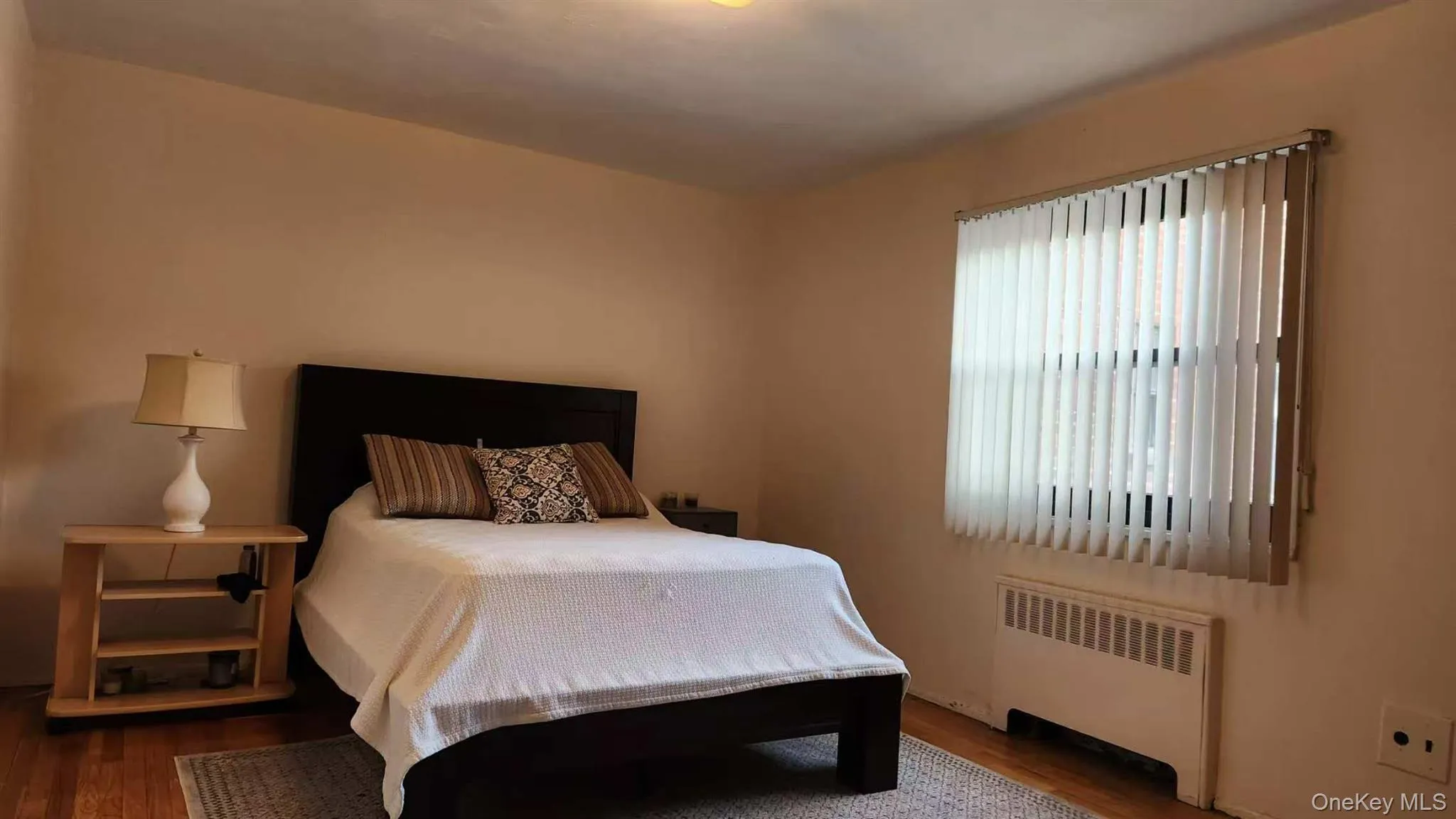 Bedroom featuring radiator and wood finished floors Bedroom featuring radiator and wood finished floors