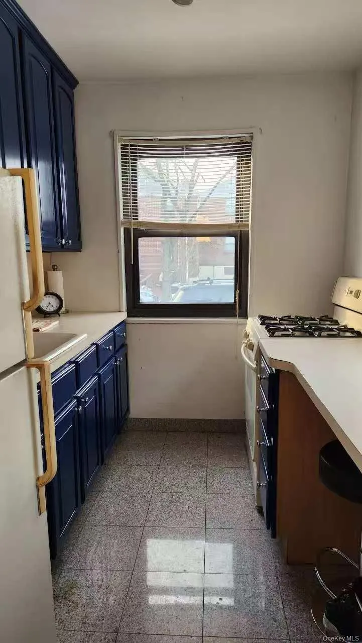 Kitchen featuring light countertops, blue cabinetry, gas range oven, and freestanding refrigerator Kitchen featuring light countertops, blue cabinetry, gas range oven, and freestanding refrigerator