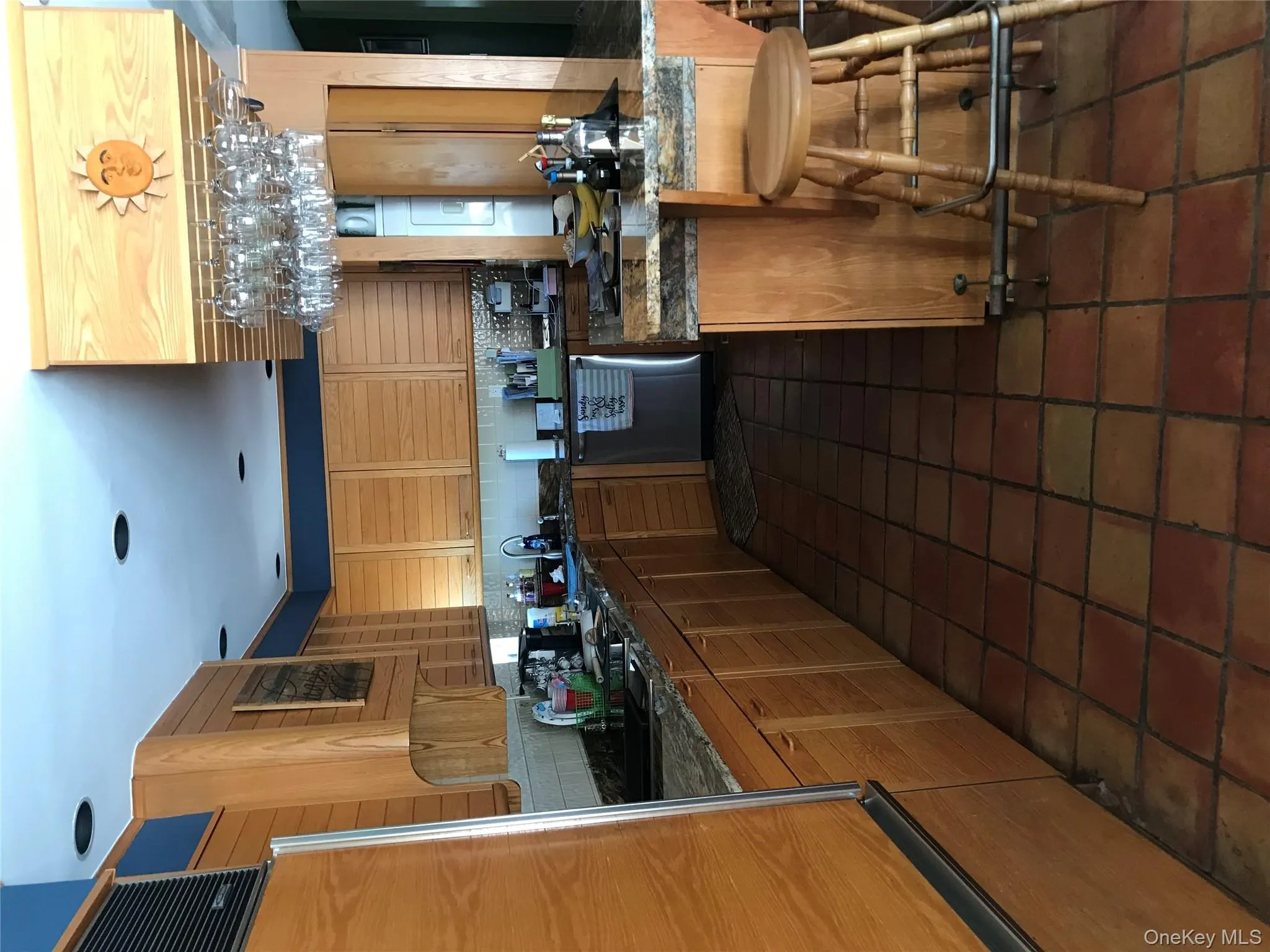 Kitchen with dark stone counters, backsplash, a breakfast bar area, dishwasher, and refrigerator Kitchen with dark stone counters, backsplash, a breakfast bar area, dishwasher, and refrigerator