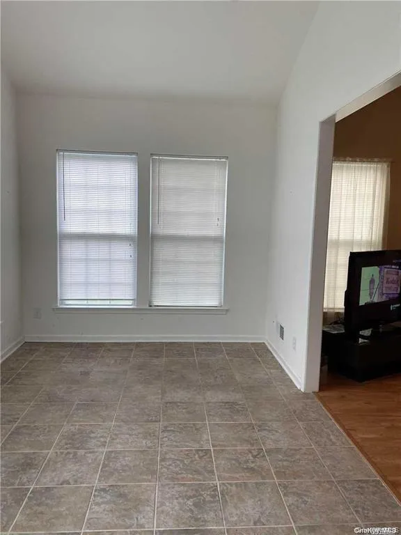 Unfurnished room featuring healthy amount of natural light and vaulted ceiling Unfurnished room featuring healthy amount of natural light and vaulted ceiling