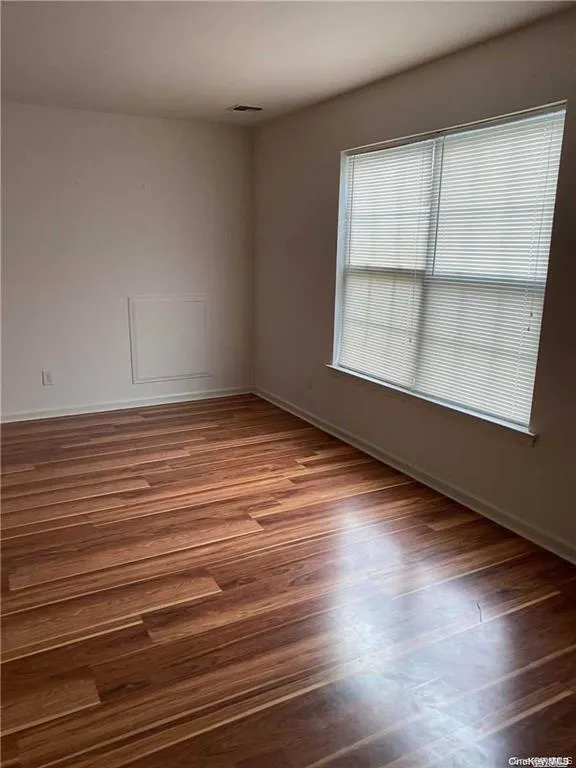 Spare room with dark wood-type flooring and baseboards Spare room with dark wood-type flooring and baseboards