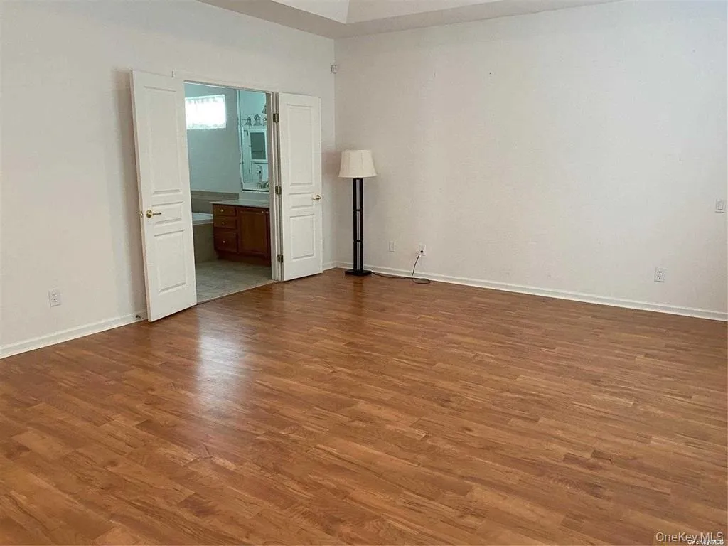 Unfurnished bedroom with dark wood finished floors and ensuite bath Unfurnished bedroom with dark wood finished floors and ensuite bath