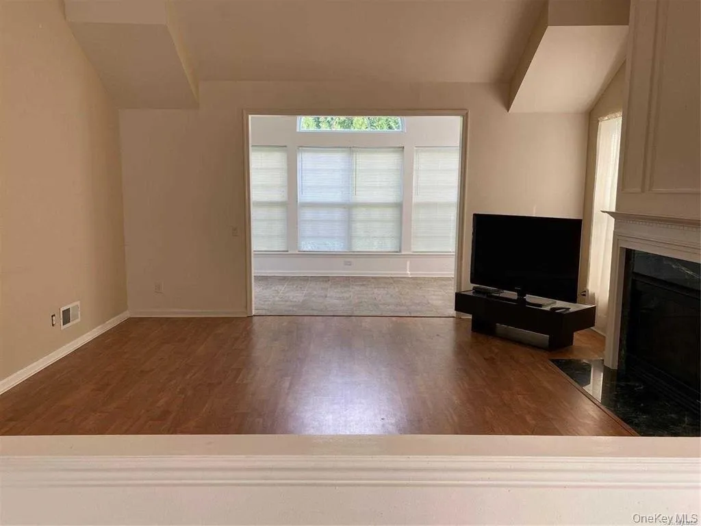 Unfurnished living room with a premium fireplace, dark wood-style floors, and vaulted ceiling Unfurnished living room with a premium fireplace, dark wood-style floors, and vaulted ceiling