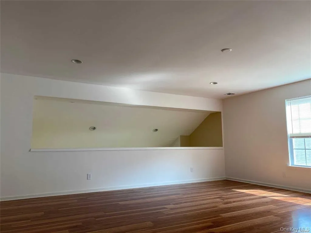 Spare room with dark wood-style flooring and lofted ceiling Spare room with dark wood-style flooring and lofted ceiling