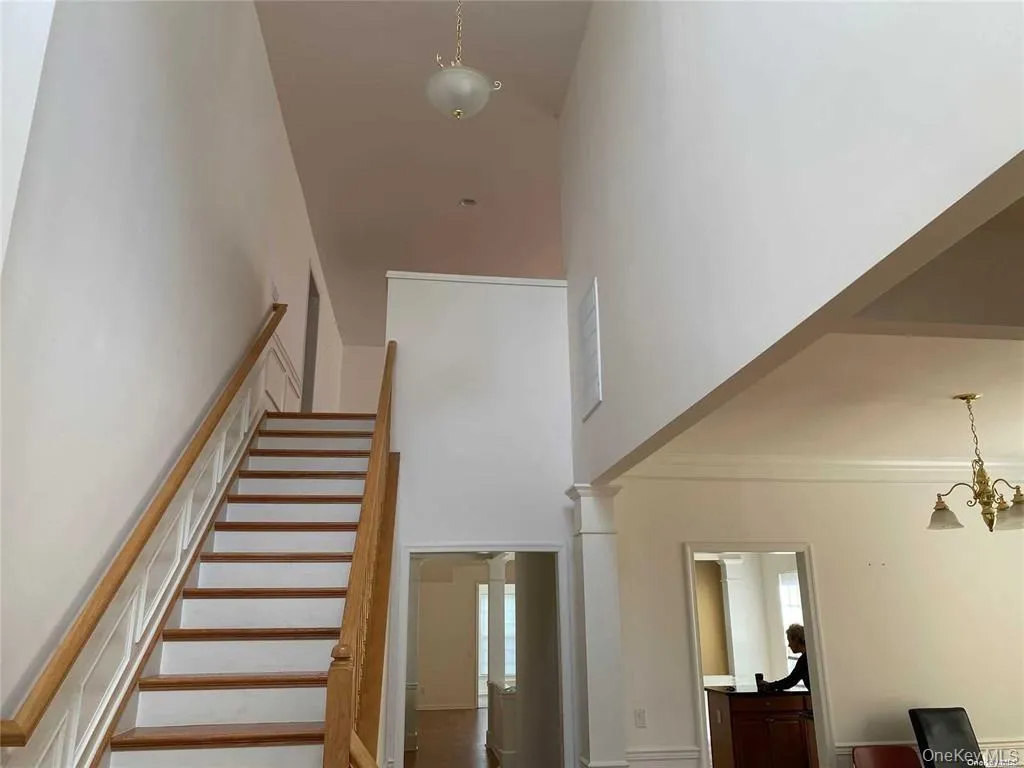 Stairway featuring a chandelier, a towering ceiling, and ornamental molding Stairway featuring a chandelier, a towering ceiling, and ornamental molding