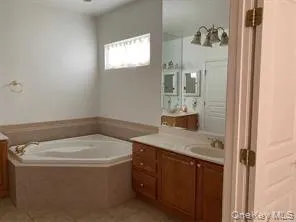 Bathroom featuring vanity, light tile patterned flooring, and a bath Bathroom featuring vanity, light tile patterned flooring, and a bath