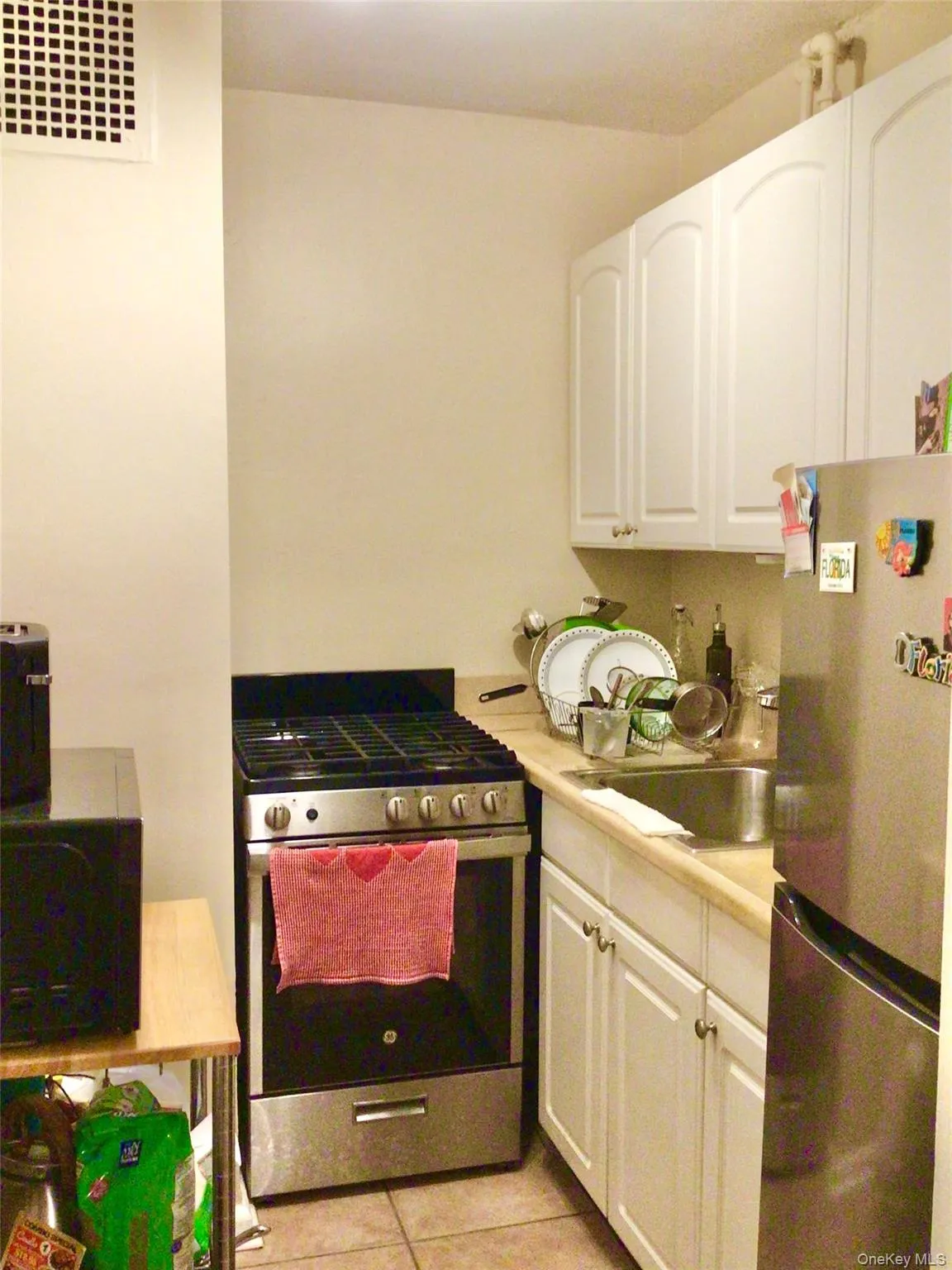 Kitchen featuring stainless steel appliances, light countertops, white cabinetry, and light tile patterned floors Kitchen featuring stainless steel appliances, light countertops, white cabinetry, and light tile patterned floors