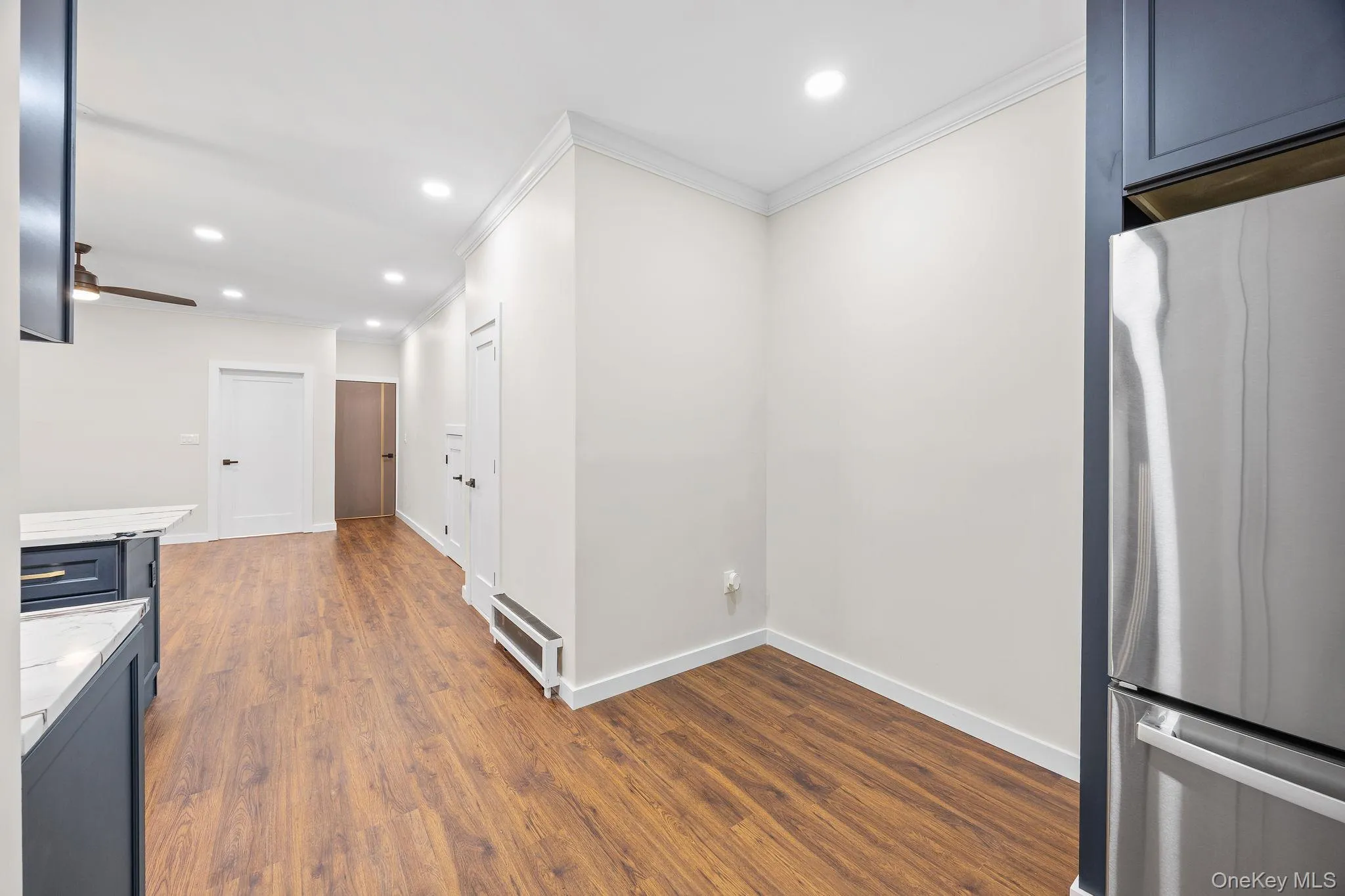 Kitchen featuring freestanding refrigerator, light stone countertops, ornamental molding, recessed lighting, and blue cabinetry Kitchen featuring freestanding refrigerator, light stone countertops, ornamental molding, recessed lighting, and blue cabinetry