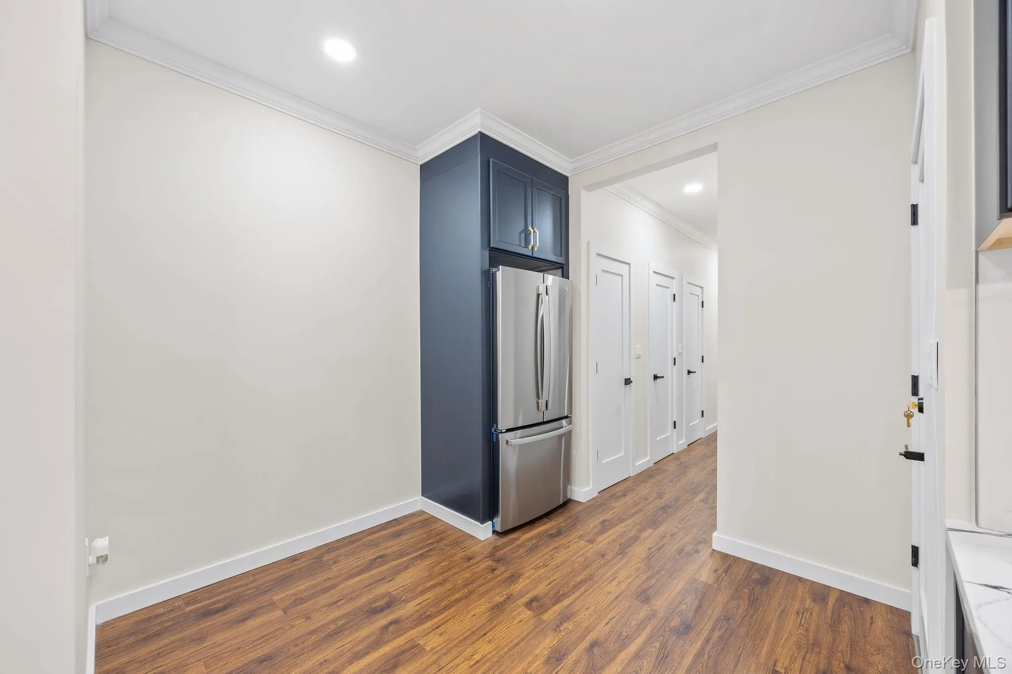 Empty room with recessed lighting, dark wood finished floors, and crown molding Empty room with recessed lighting, dark wood finished floors, and crown molding