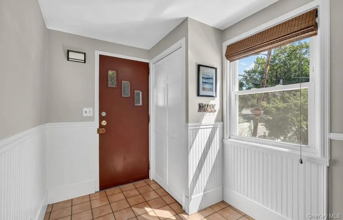 Foyer entrance features the coat closet, tile floors and a wainscoted wall Foyer entrance features the coat closet, tile floors and a wainscoted wall