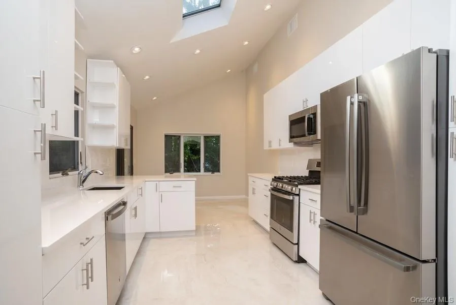 Kitchen with stainless steel appliances, open shelves, light marble finish floors, a skylight, and recessed lighting Kitchen with stainless steel appliances, open shelves, light marble finish floors, a skylight, and recessed lighting