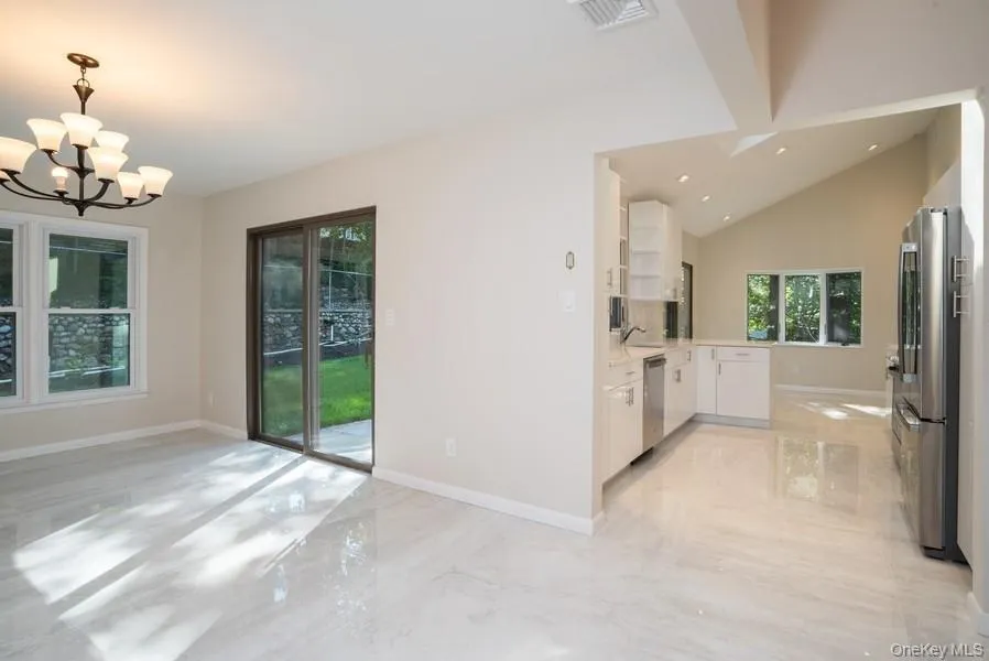 Kitchen with stainless steel appliances, white cabinetry, light countertops, light marble finish flooring, and a chandelier Kitchen with stainless steel appliances, white cabinetry, light countertops, light marble finish flooring, and a chandelier