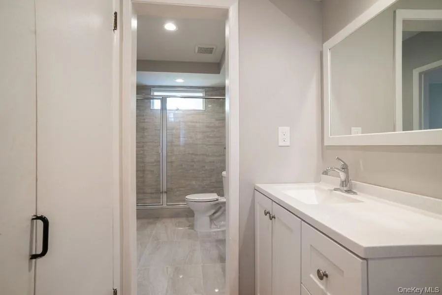 Bathroom with vanity, a shower stall, marble look tiles, and recessed lighting Bathroom with vanity, a shower stall, marble look tiles, and recessed lighting