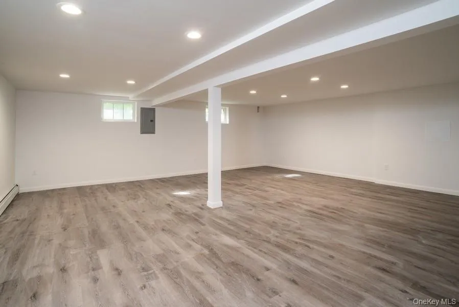 Below grade area with electric panel, recessed lighting, and wood finished floors Below grade area with electric panel, recessed lighting, and wood finished floors