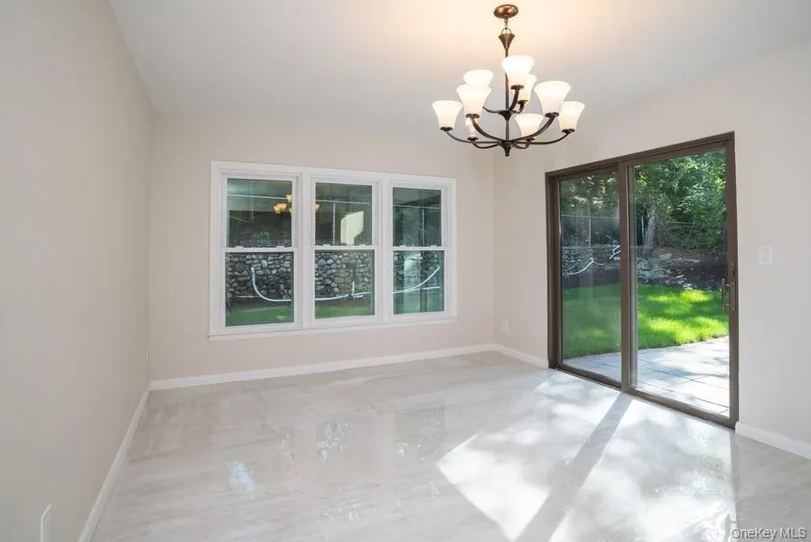 Empty room featuring a chandelier and baseboards Empty room featuring a chandelier and baseboards