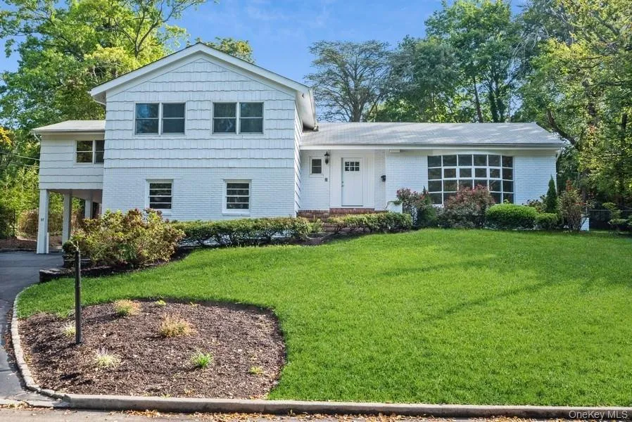 Split level home with a front lawn, a carport, brick siding, and asphalt driveway Split level home with a front lawn, a carport, brick siding, and asphalt driveway