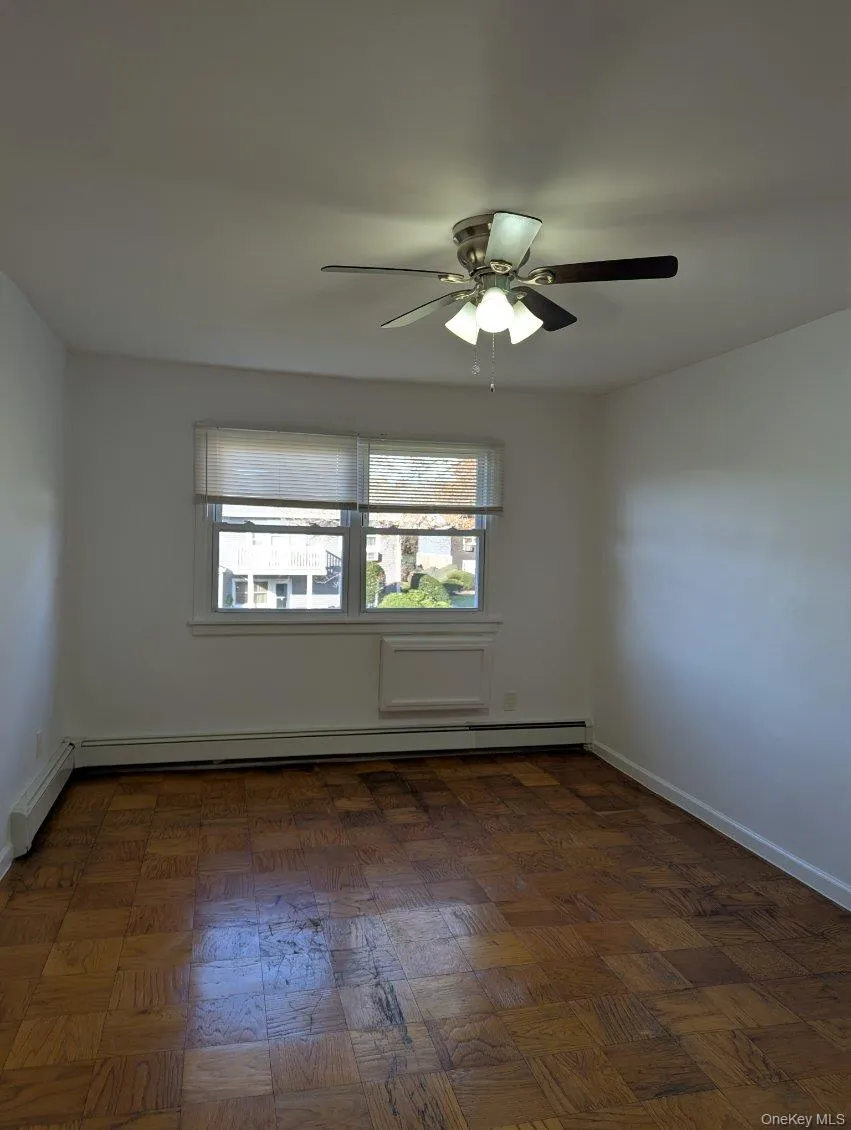 Empty room with healthy amount of natural light, a baseboard heating unit, and a ceiling fan Empty room with healthy amount of natural light, a baseboard heating unit, and a ceiling fan