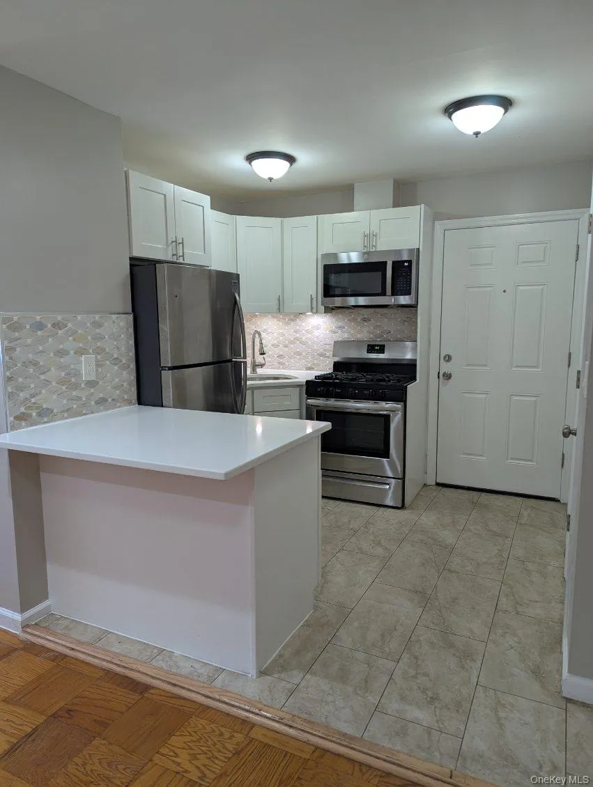 Kitchen featuring stainless steel appliances, a peninsula, white cabinets, and decorative backsplash Kitchen featuring stainless steel appliances, a peninsula, white cabinets, and decorative backsplash