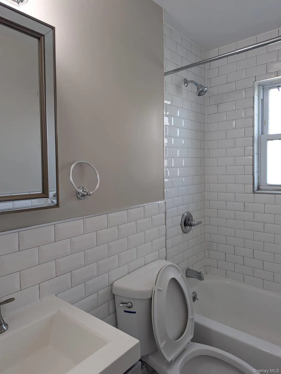 Bathroom featuring tub / shower combination, tile walls, vanity, and wainscoting Bathroom featuring tub / shower combination, tile walls, vanity, and wainscoting