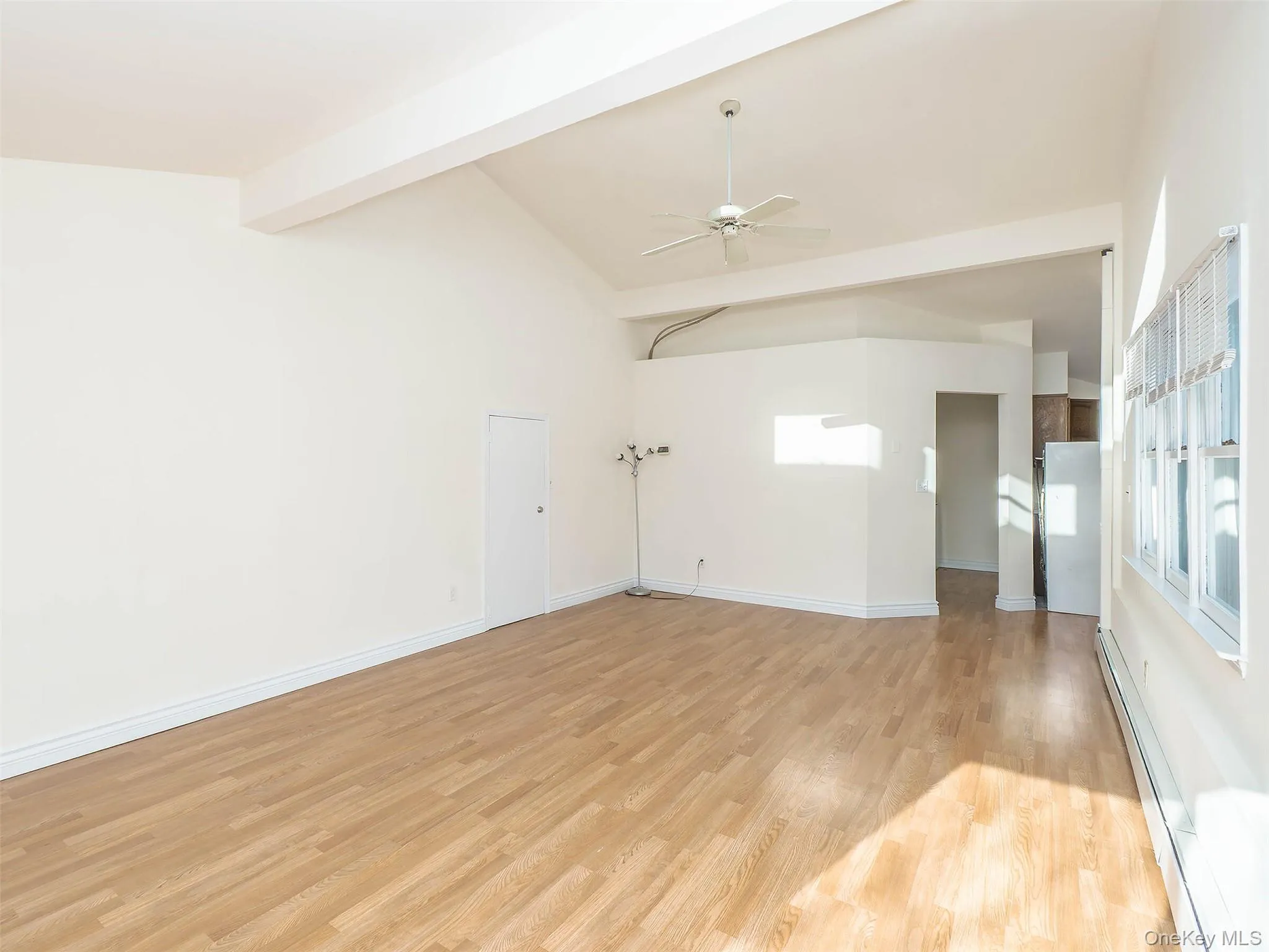 Empty room featuring baseboard heating, light wood finished floors, and ceiling fan Empty room featuring baseboard heating, light wood finished floors, and ceiling fan