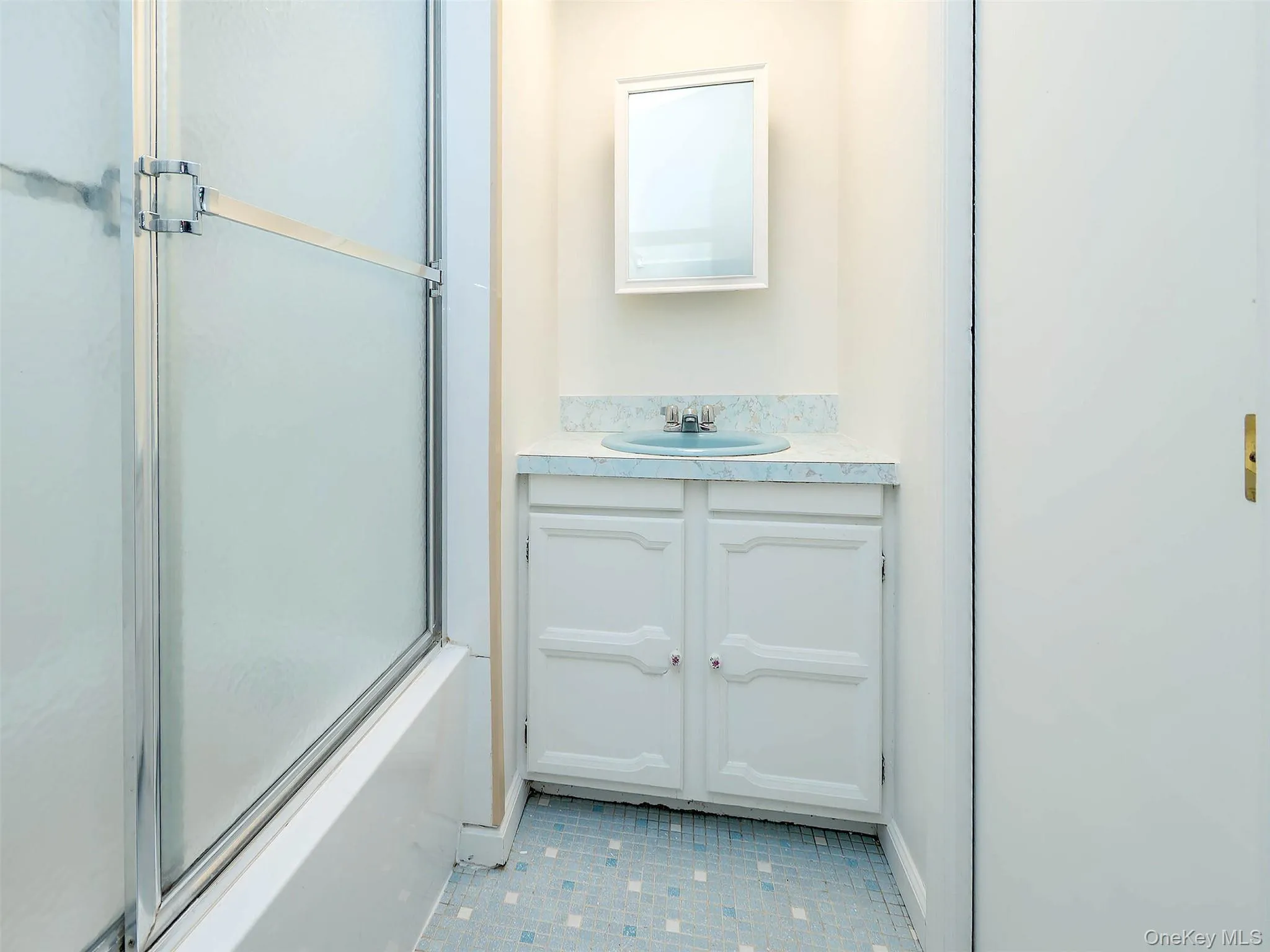 Bathroom with vanity, enclosed tub / shower combo, and light tile patterned floors Bathroom with vanity, enclosed tub / shower combo, and light tile patterned floors