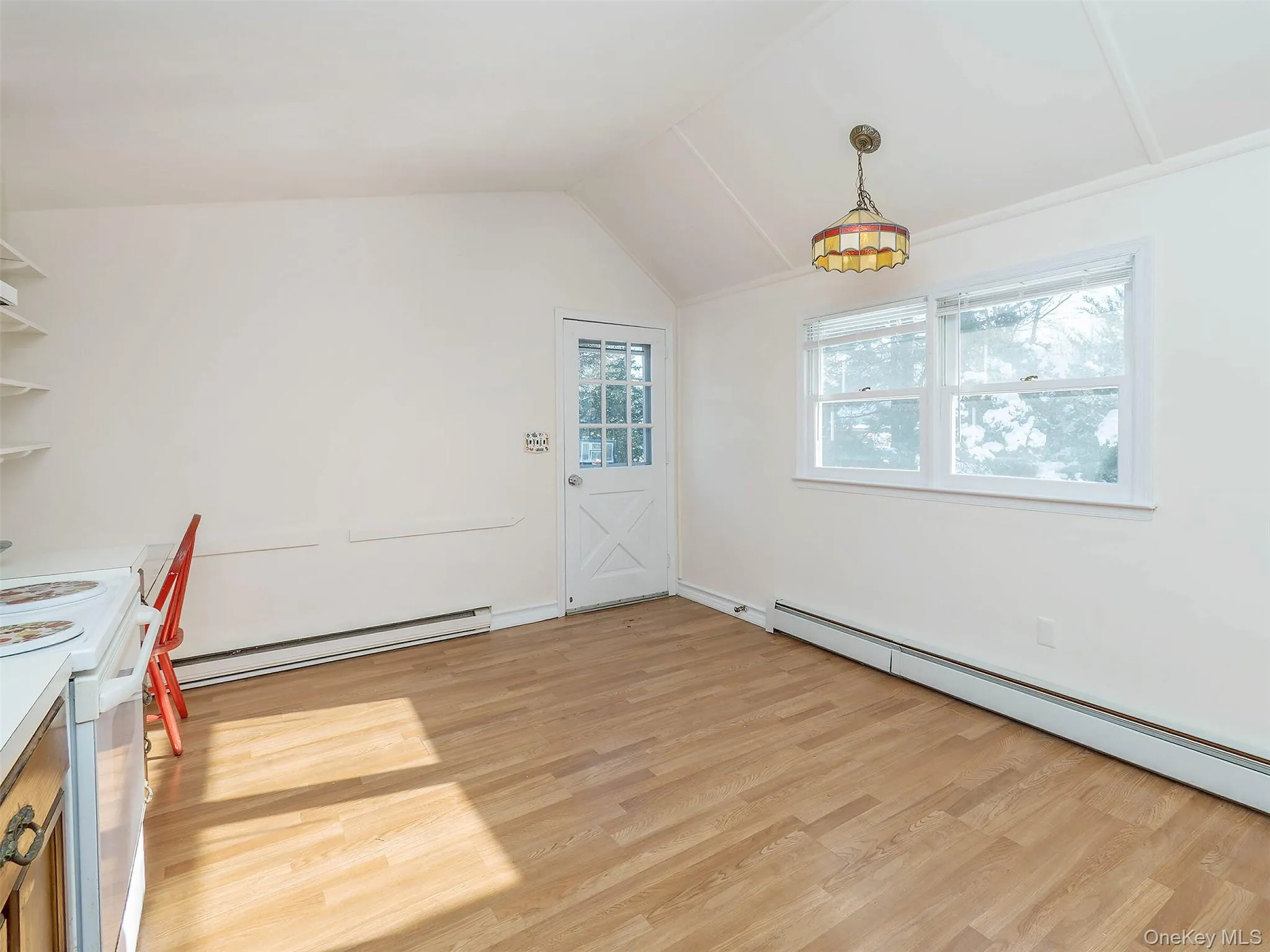 Unfurnished dining area with baseboard heating, vaulted ceiling, a baseboard radiator, and light wood-style floors Unfurnished dining area with baseboard heating, vaulted ceiling, a baseboard radiator, and light wood-style floors