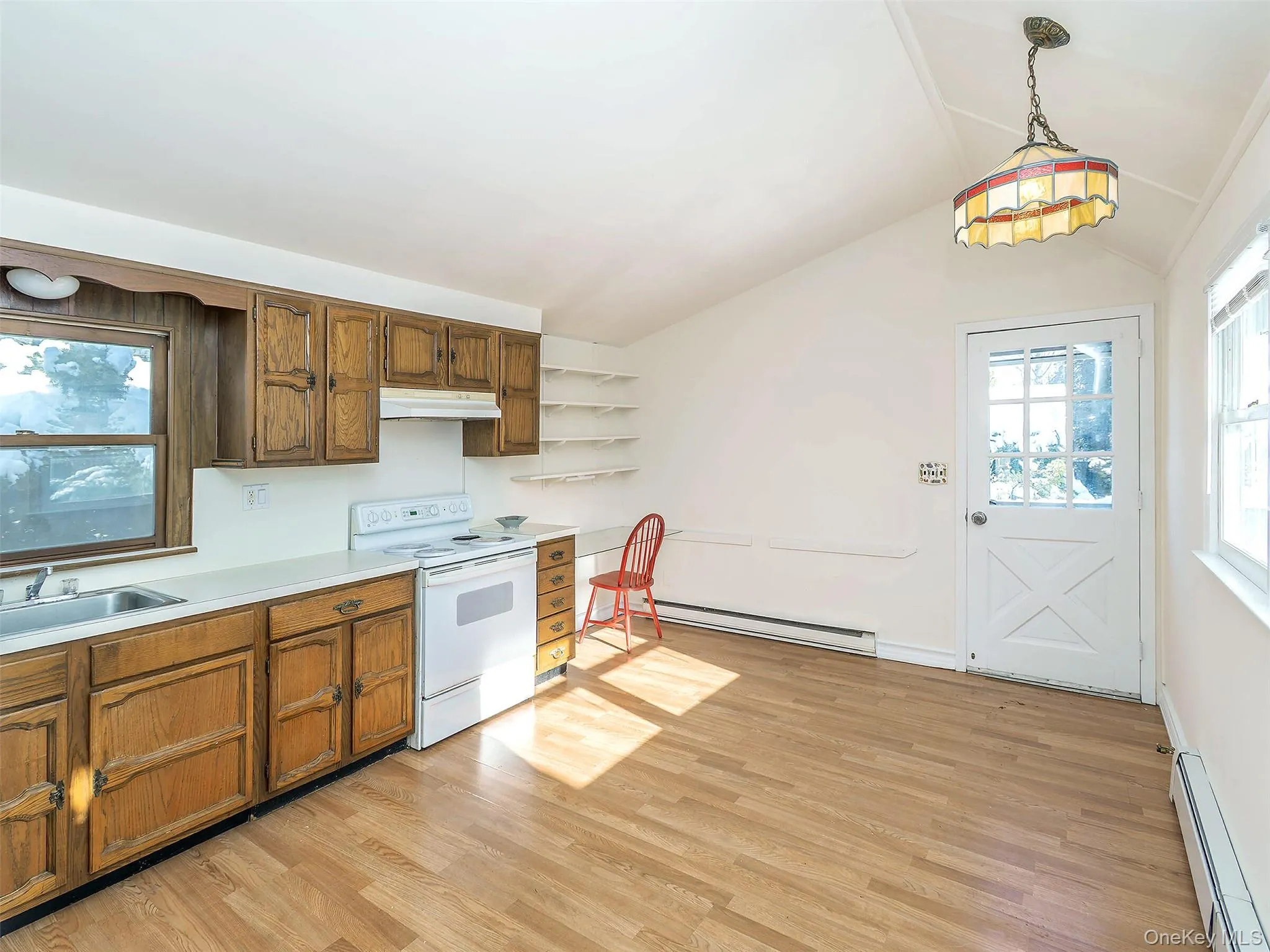 Kitchen featuring electric stove, light countertops, a baseboard radiator, light wood finished floors, and vaulted ceiling Kitchen featuring electric stove, light countertops, a baseboard radiator, light wood finished floors, and vaulted ceiling