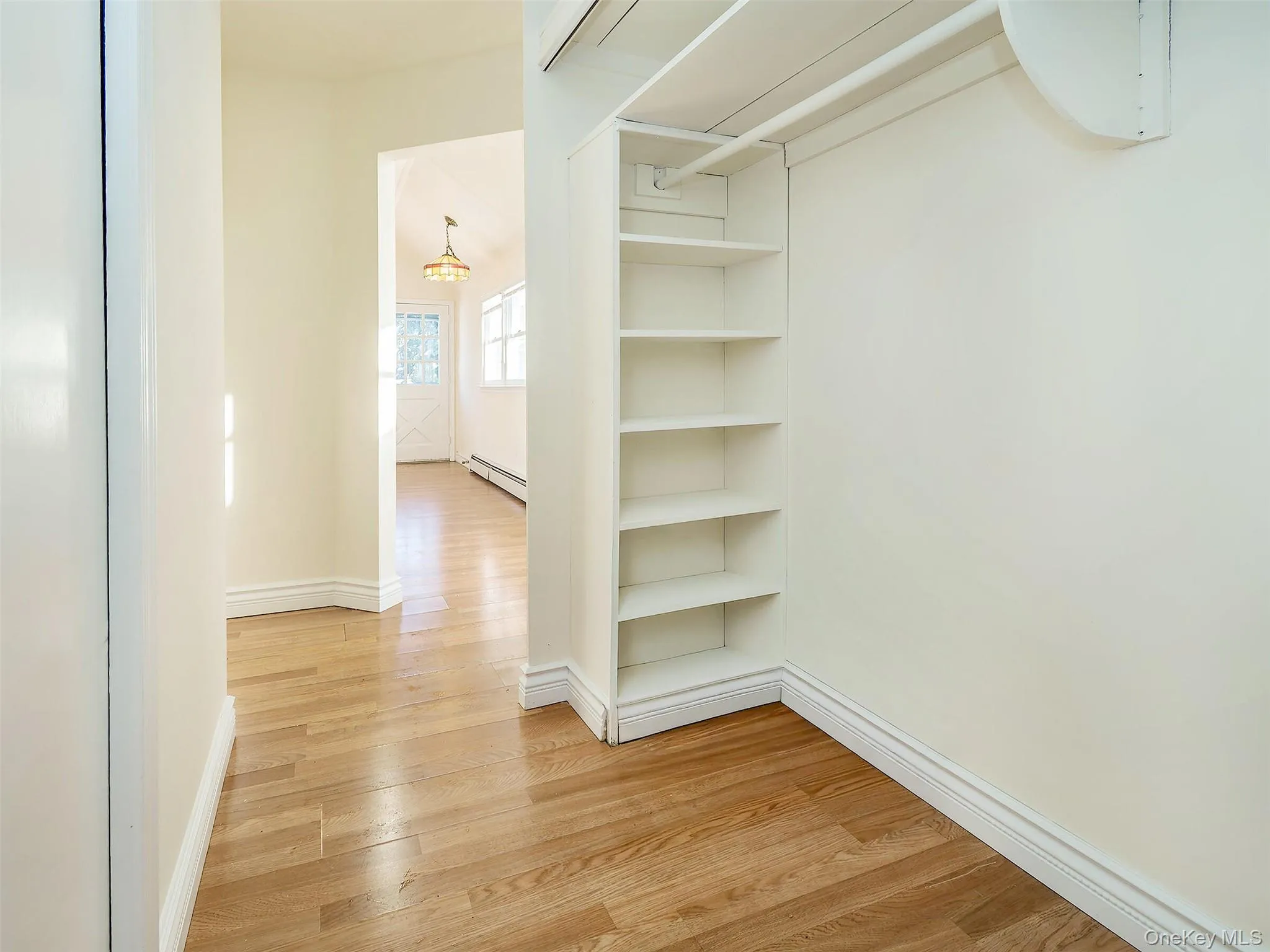 Walk in closet with light wood-style flooring and baseboard heating Walk in closet with light wood-style flooring and baseboard heating