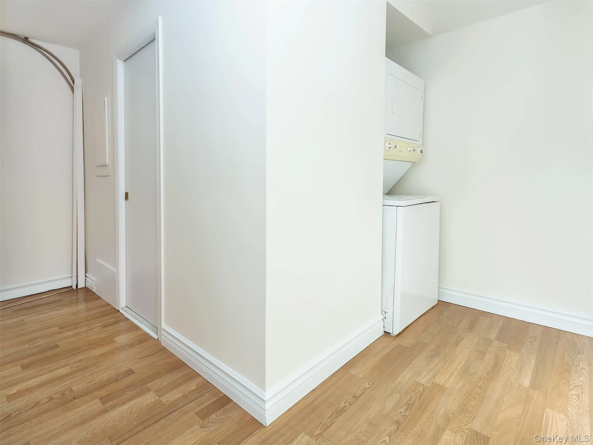 Laundry area with light wood-style flooring and stacked washer / drying machine Laundry area with light wood-style flooring and stacked washer / drying machine