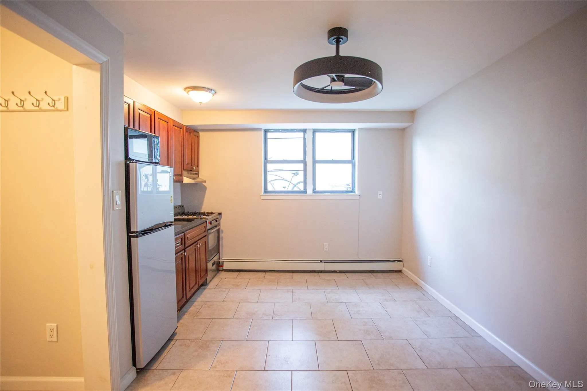 Kitchen with appliances with stainless steel finishes, plenty of natural light, brown cabinets, and a baseboard radiator Kitchen with appliances with stainless steel finishes, plenty of natural light, brown cabinets, and a baseboard radiator