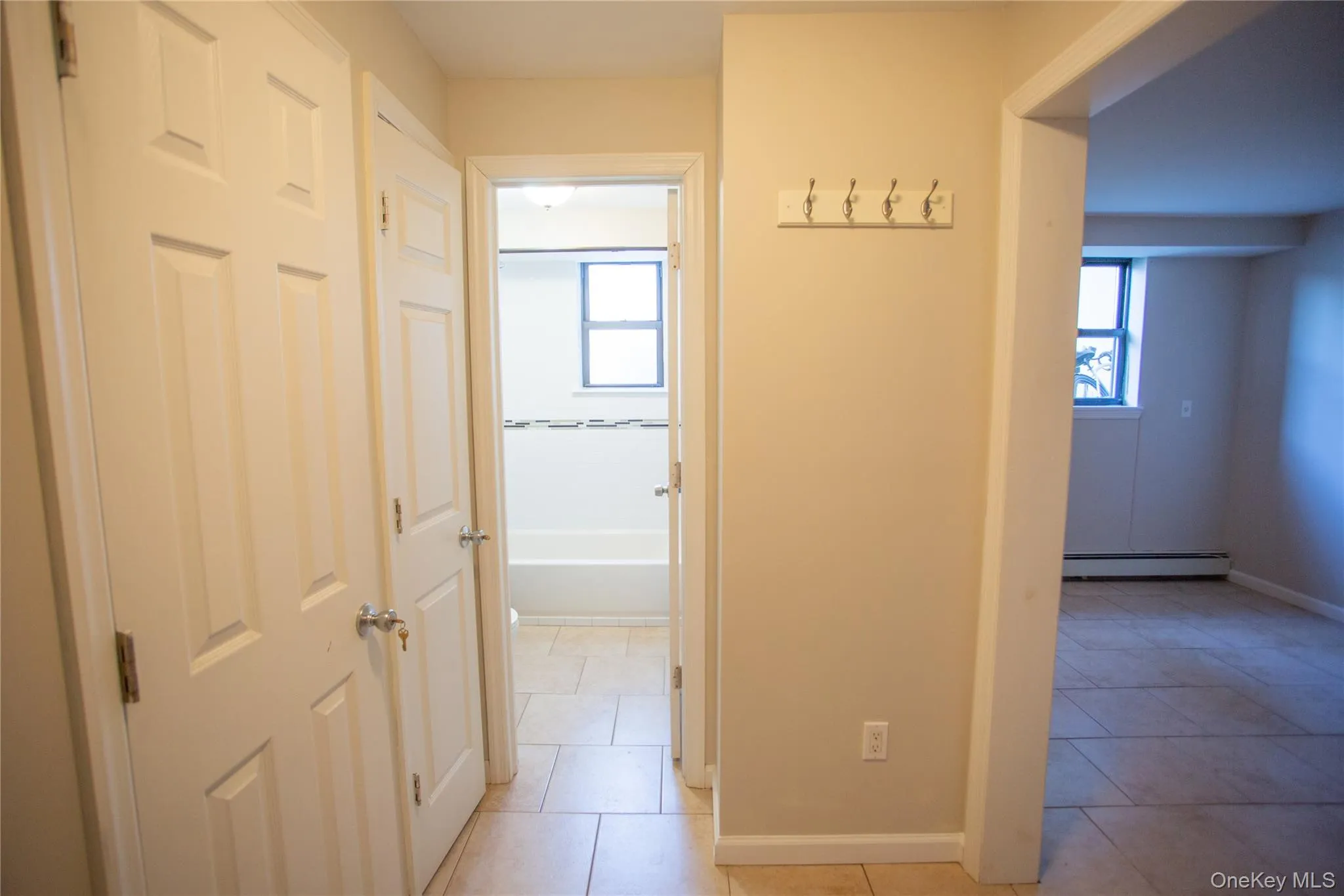 Hall featuring plenty of natural light, light tile patterned floors, and a baseboard heating unit Hall featuring plenty of natural light, light tile patterned floors, and a baseboard heating unit