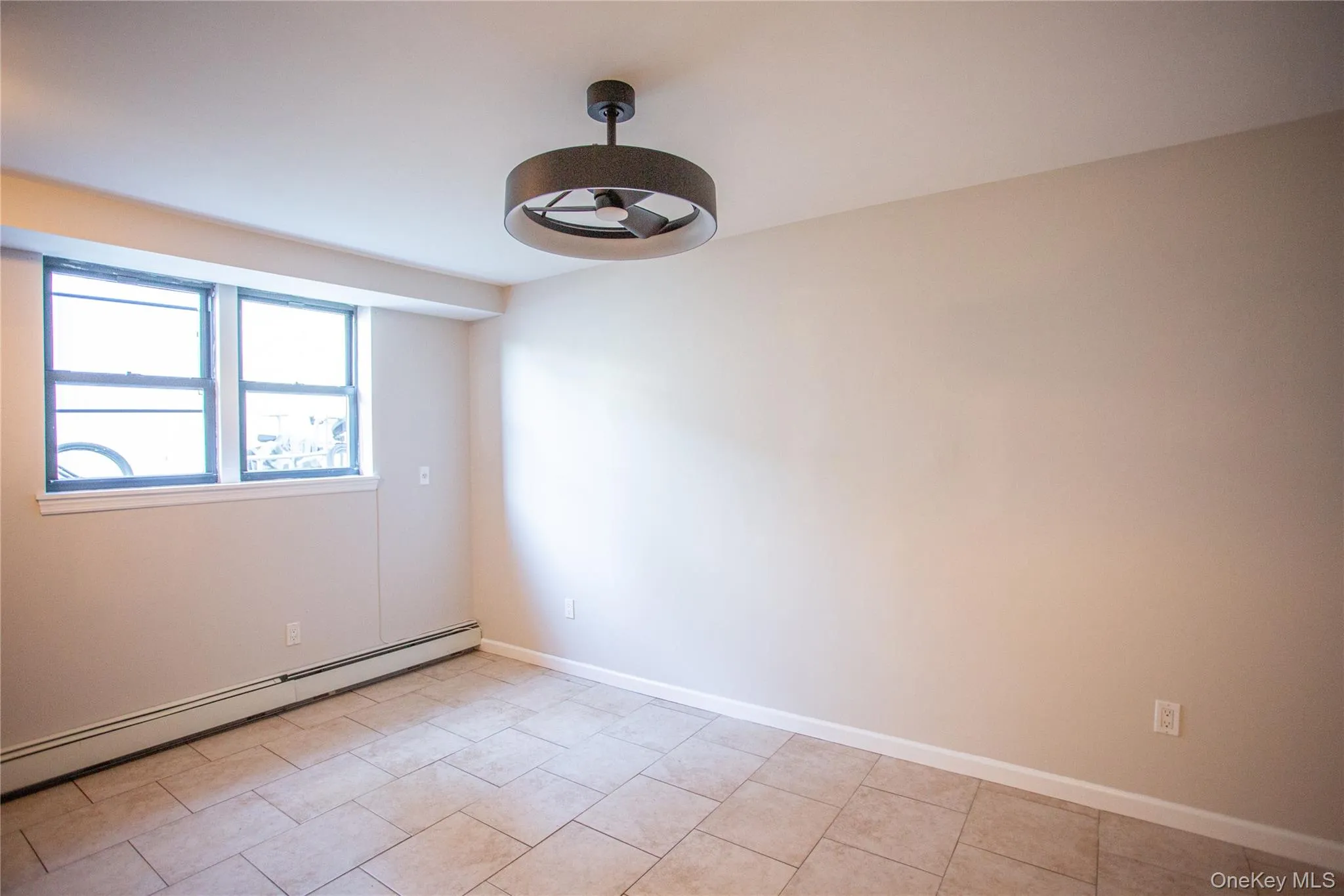 Spare room with baseboard heating and light tile patterned floors Spare room with baseboard heating and light tile patterned floors