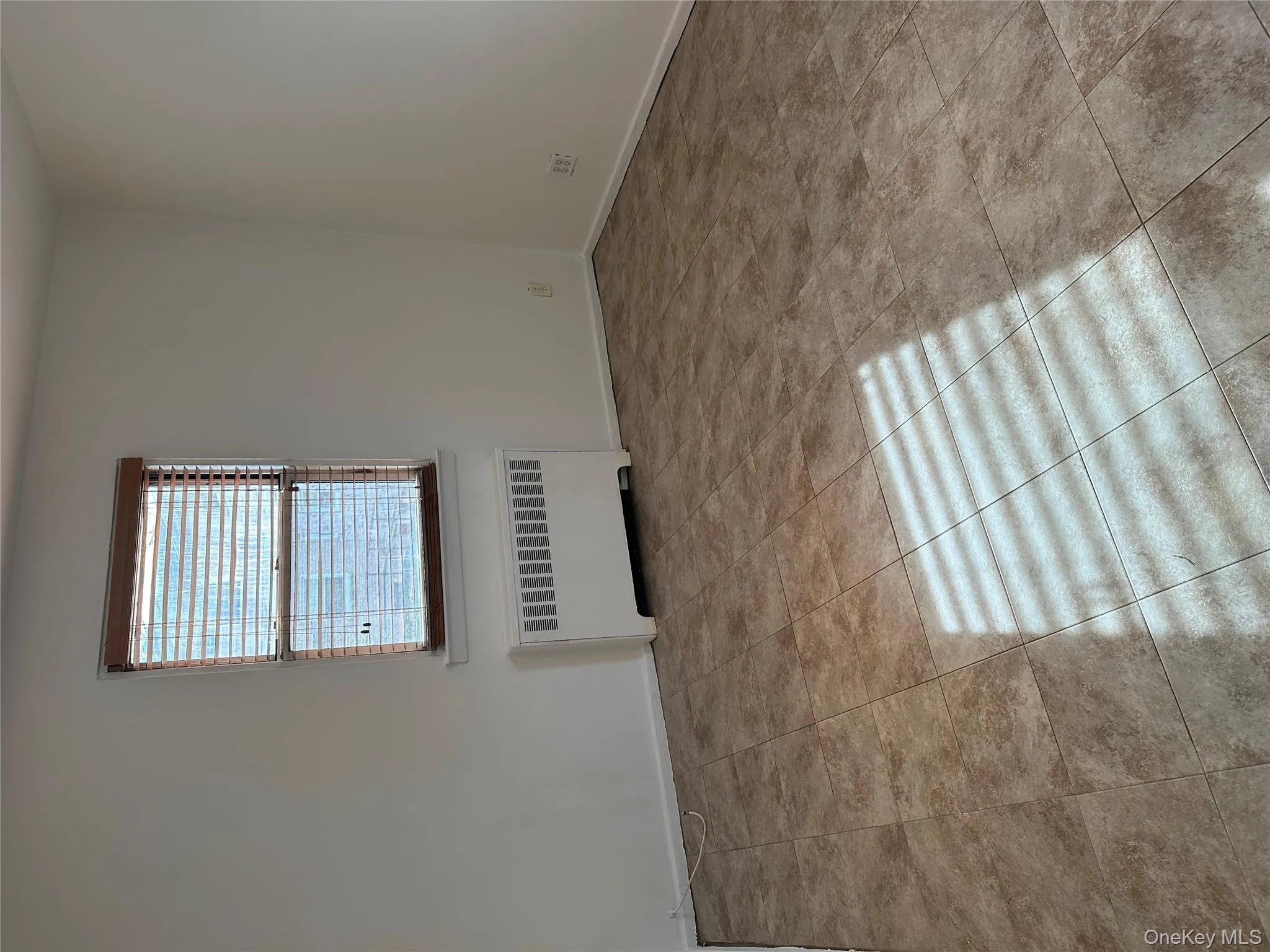 Empty room featuring radiator heating unit and light tile patterned floors Empty room featuring radiator heating unit and light tile patterned floors