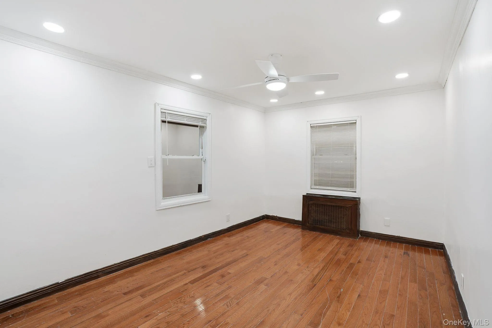 Spare room with radiator, hardwood / wood-style flooring, ornamental molding, recessed lighting, and ceiling fan Spare room with radiator, hardwood / wood-style flooring, ornamental molding, recessed lighting, and ceiling fan