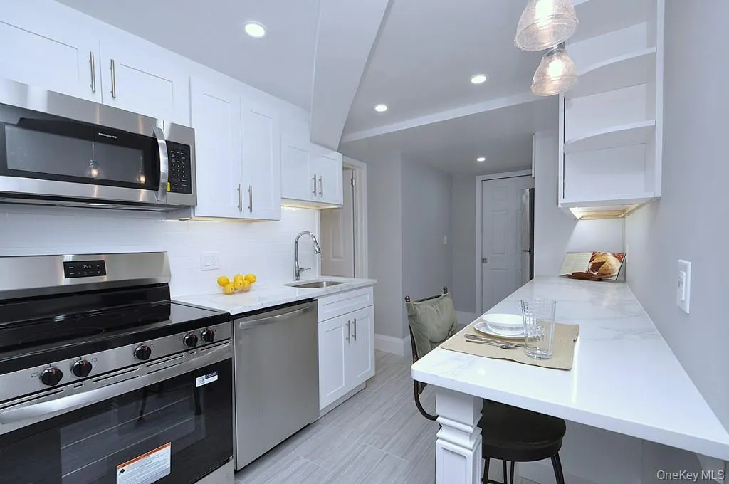 Fully renovated eat-in-kitchen has quartz counters, stainless steel appliances including a dishwasher, microwave, range and refrigerator. The white cabinets and pantry provide plenty of storage for the chef in you. The counter offer a place to have a meal with pendant lighting. The kitchen is approx 15' x 7'-4". Fully renovated eat-in-kitchen has quartz counters, stainless steel appliances including a dishwasher, microwave, range and refrigerator. The white cabinets and pantry provide plenty of storage for the chef in you. The counter offer a place to have a meal with pendant lighting. The kitchen is approx 15' x 7'-4".