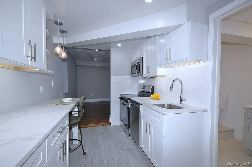 Fully renovated eat-in-kitchen has quartz counters, stainless steel appliances including a dishwasher, microwave, range and refrigerator. The white cabinets and pantry provide plenty of storage for the chef in you. The counter offer a place to have a meal with pendant lighting. The kitchen is approx 15' x 7'-4". Fully renovated eat-in-kitchen has quartz counters, stainless steel appliances including a dishwasher, microwave, range and refrigerator. The white cabinets and pantry provide plenty of storage for the chef in you. The counter offer a place to have a meal with pendant lighting. The kitchen is approx 15' x 7'-4".