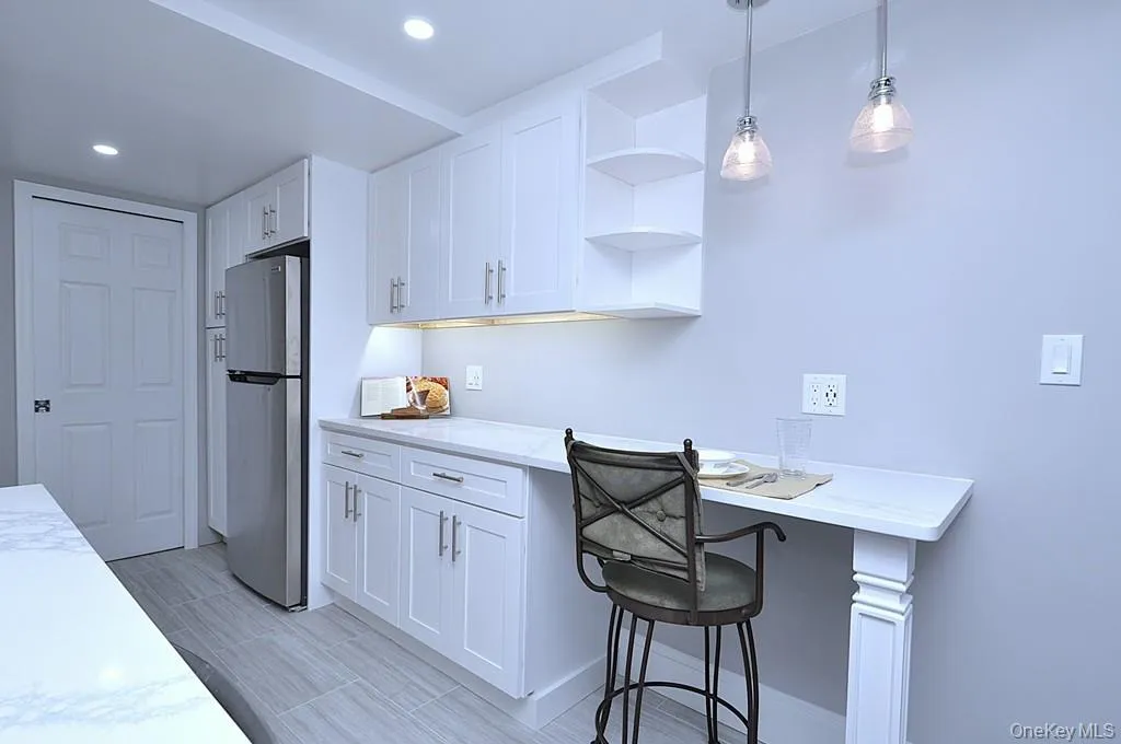 Fully renovated eat-in-kitchen has quartz counters, stainless steel appliances including a dishwasher, microwave, range and refrigerator. The white cabinets and pantry provide plenty of storage for the chef in you. The counter offer a place to have a meal with pendant lighting. The kitchen is approx 15' x 7'-4". Fully renovated eat-in-kitchen has quartz counters, stainless steel appliances including a dishwasher, microwave, range and refrigerator. The white cabinets and pantry provide plenty of storage for the chef in you. The counter offer a place to have a meal with pendant lighting. The kitchen is approx 15' x 7'-4".