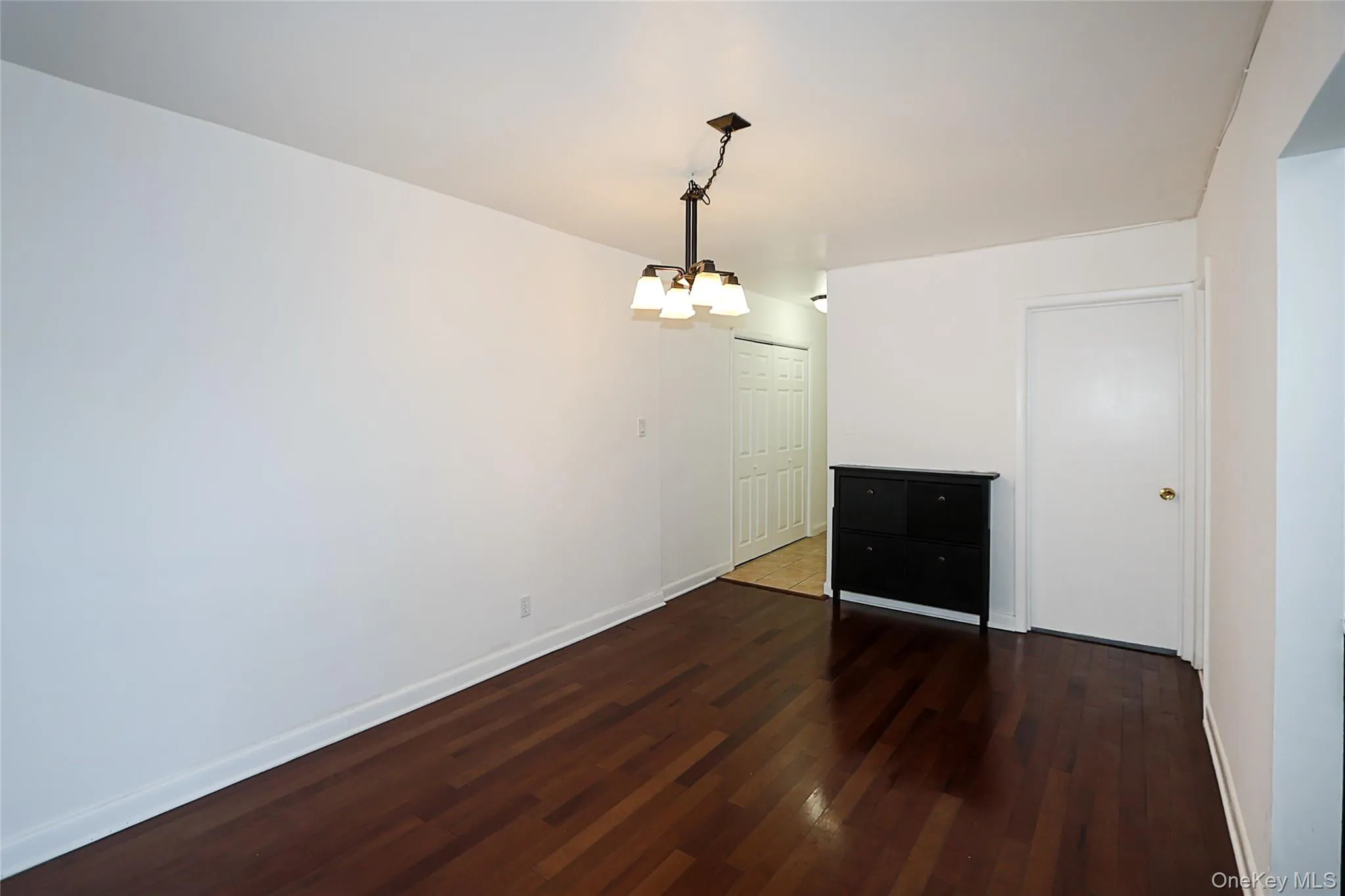 Unfurnished dining area featuring dark wood-style floors and a chandelier Unfurnished dining area featuring dark wood-style floors and a chandelier