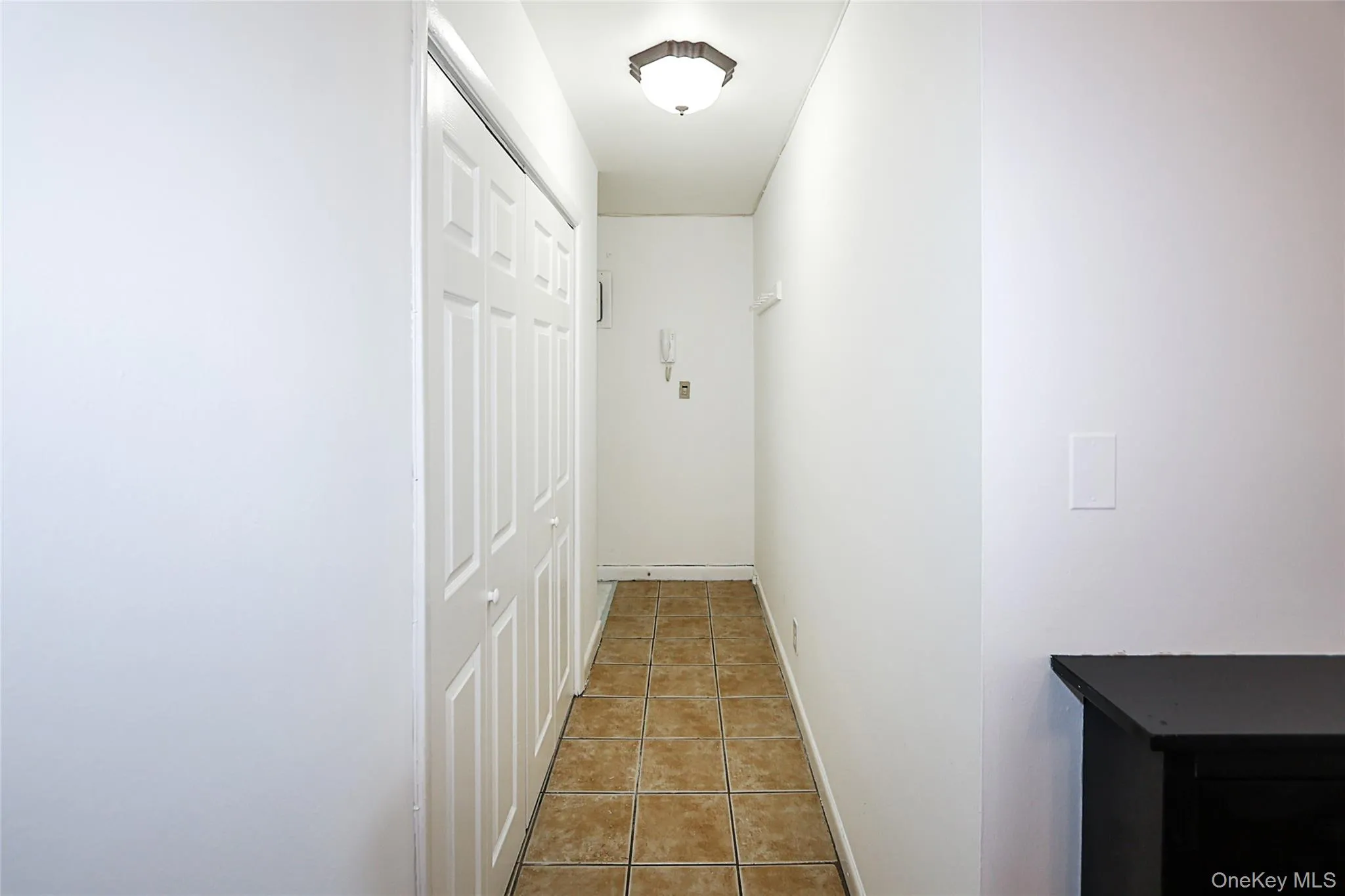 Corridor featuring light tile patterned floors and baseboards Corridor featuring light tile patterned floors and baseboards