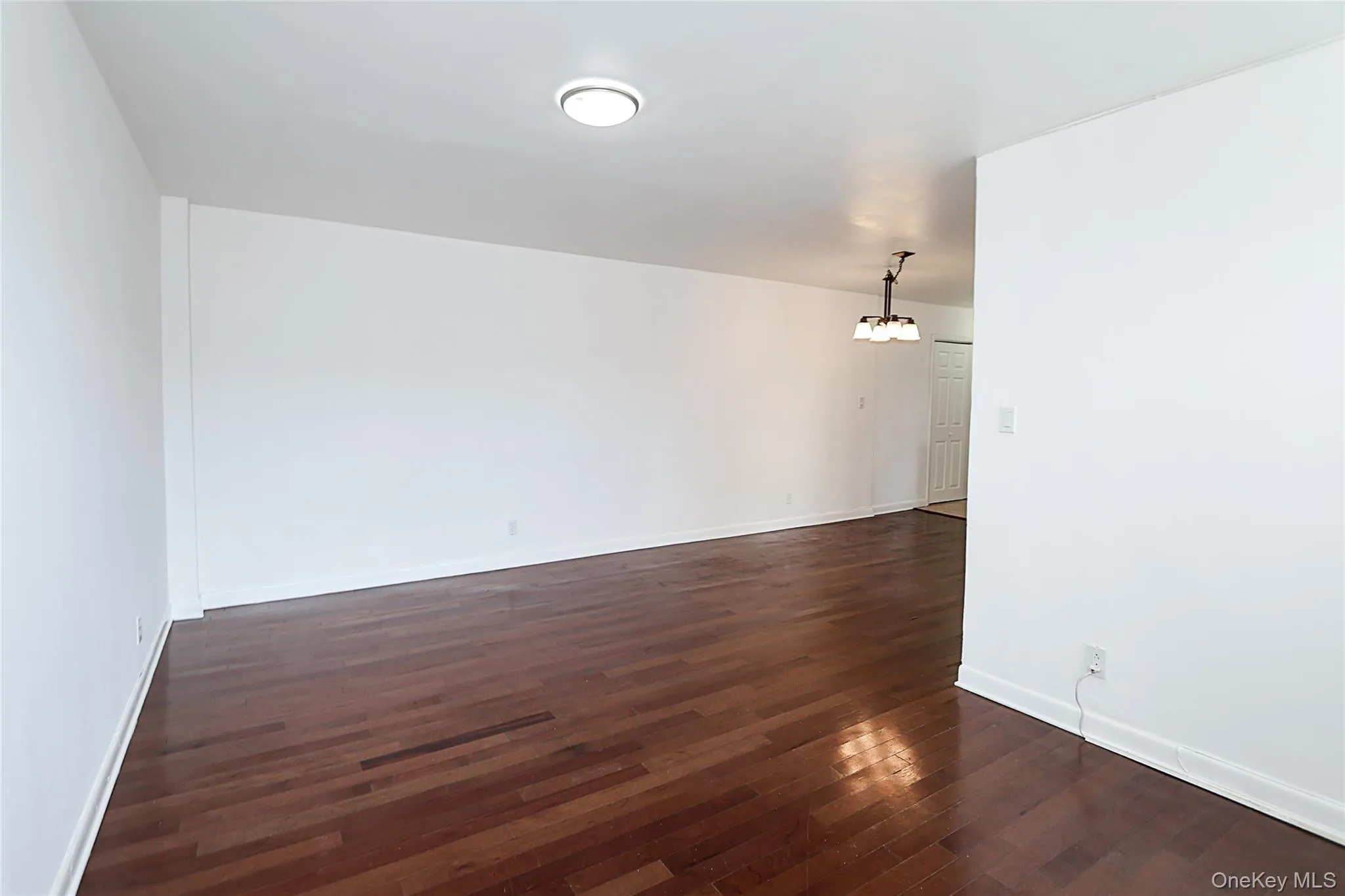 Unfurnished room with dark wood-type flooring and a chandelier Unfurnished room with dark wood-type flooring and a chandelier