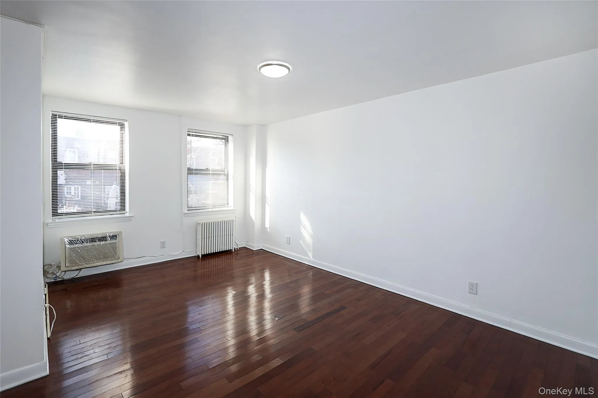 Spare room with radiator heating unit and dark wood-style flooring Spare room with radiator heating unit and dark wood-style flooring