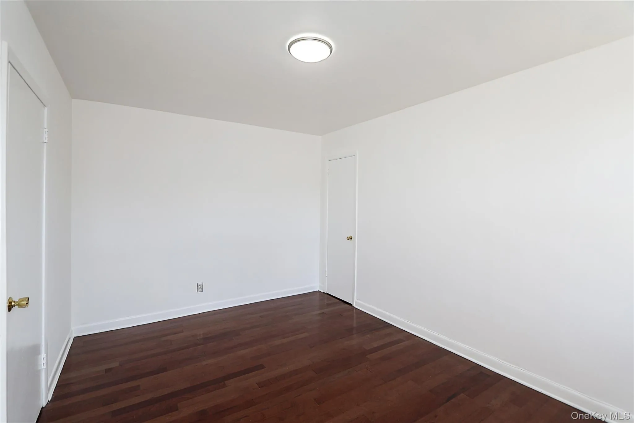 Empty room featuring dark wood-style floors and baseboards Empty room featuring dark wood-style floors and baseboards