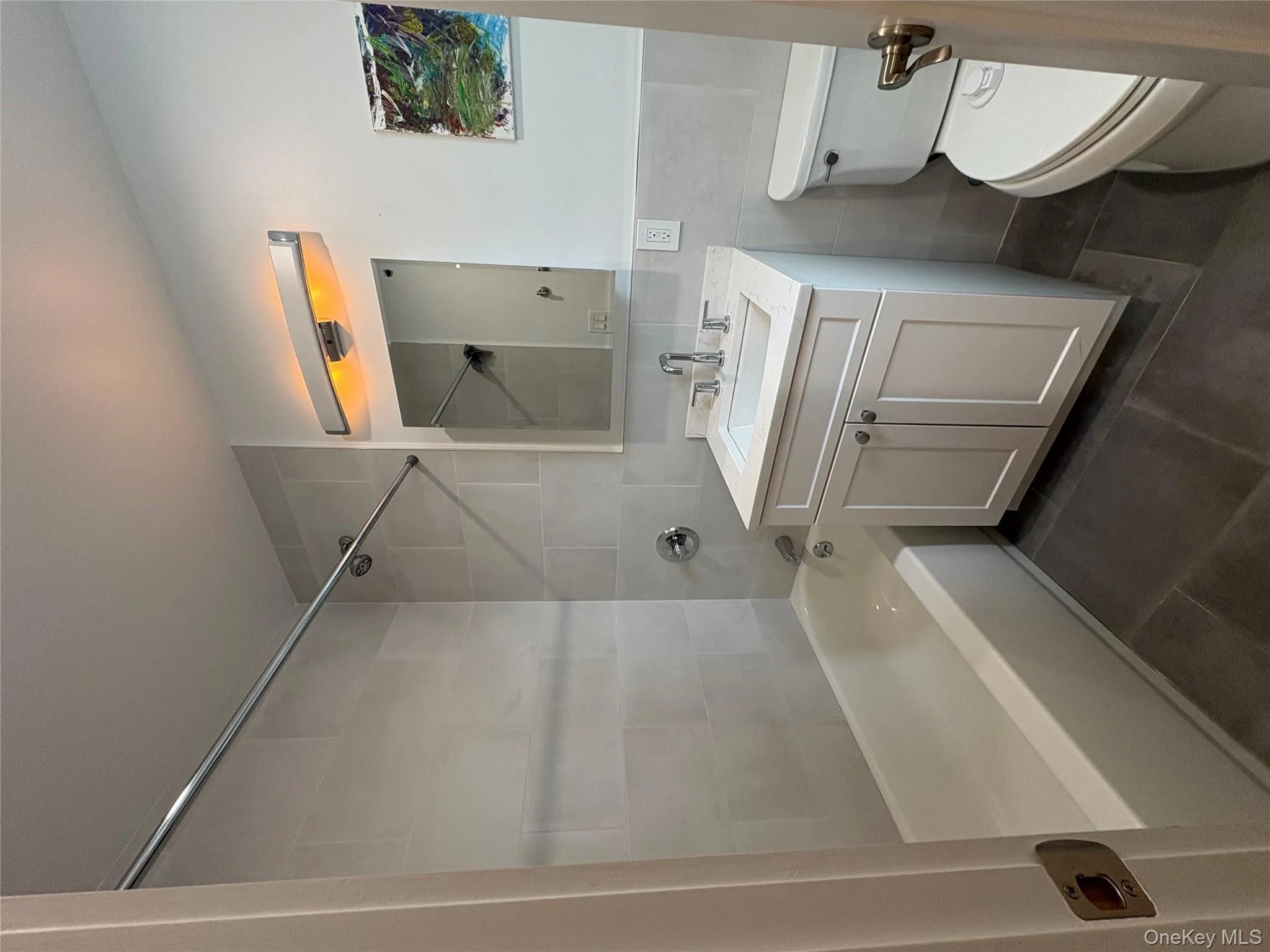 Full bath featuring vanity, bathtub / shower combination, dark tile patterned flooring, and tile walls Full bath featuring vanity, bathtub / shower combination, dark tile patterned flooring, and tile walls