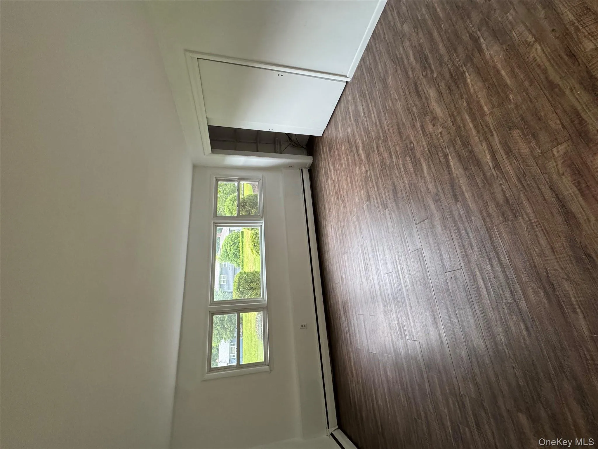 Unfurnished bedroom with dark wood-style floors, a baseboard heating unit, and a closet Unfurnished bedroom with dark wood-style floors, a baseboard heating unit, and a closet