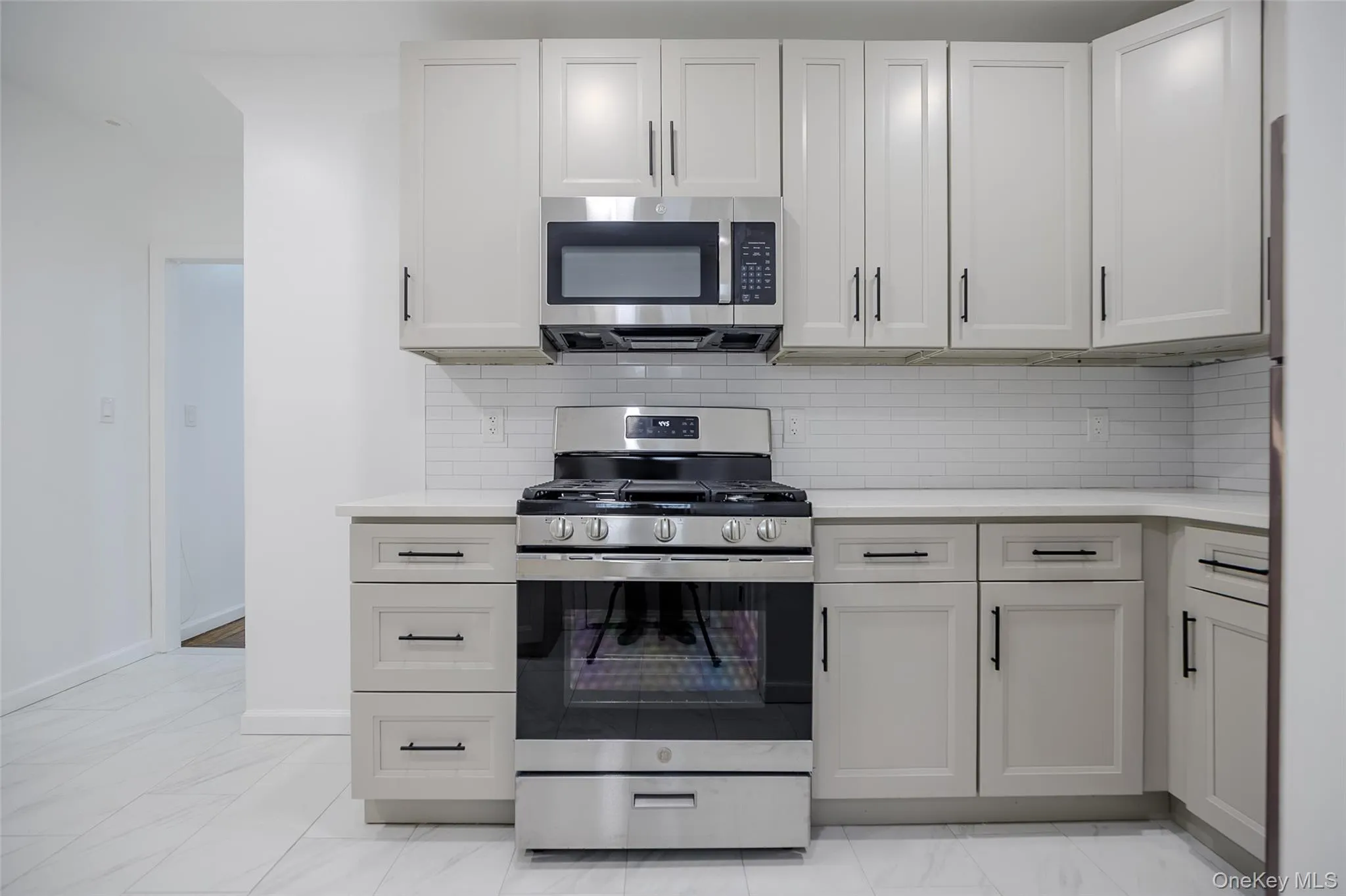 Kitchen featuring stainless steel appliances, light marble finish flooring, decorative backsplash, and light stone counters Kitchen featuring stainless steel appliances, light marble finish flooring, decorative backsplash, and light stone counters
