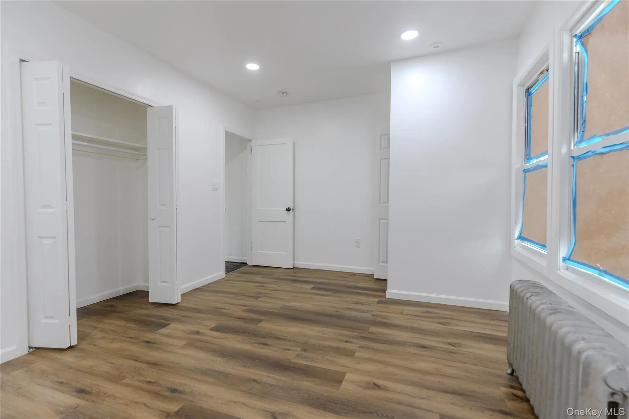 Unfurnished bedroom with radiator, wood finished floors, recessed lighting, and a closet Unfurnished bedroom with radiator, wood finished floors, recessed lighting, and a closet