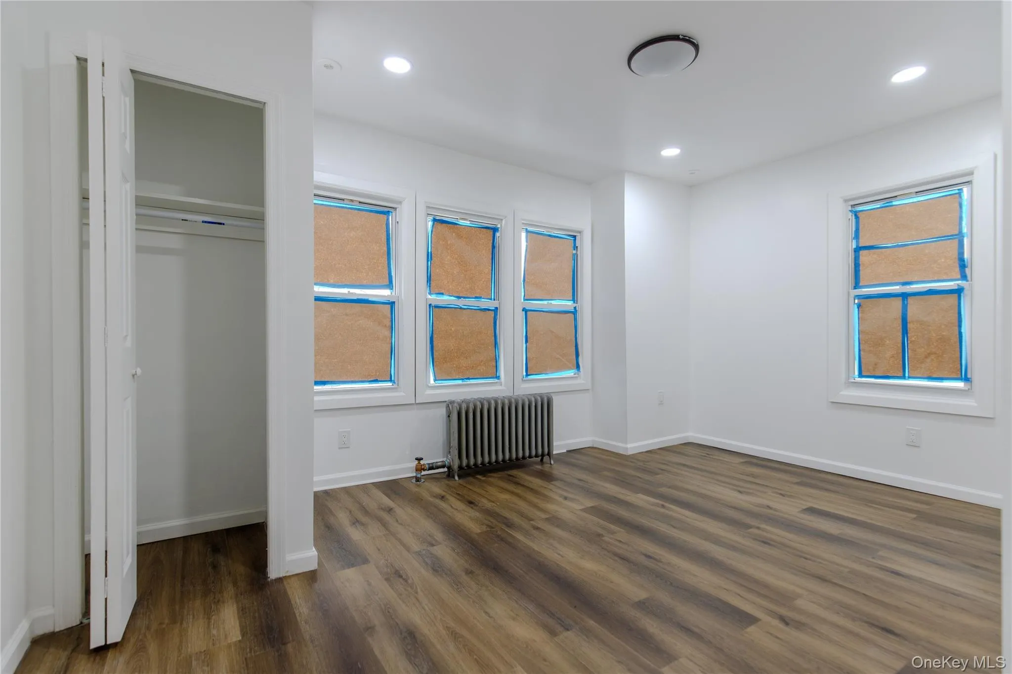 Unfurnished bedroom featuring radiator heating unit, dark wood-type flooring, and recessed lighting Unfurnished bedroom featuring radiator heating unit, dark wood-type flooring, and recessed lighting