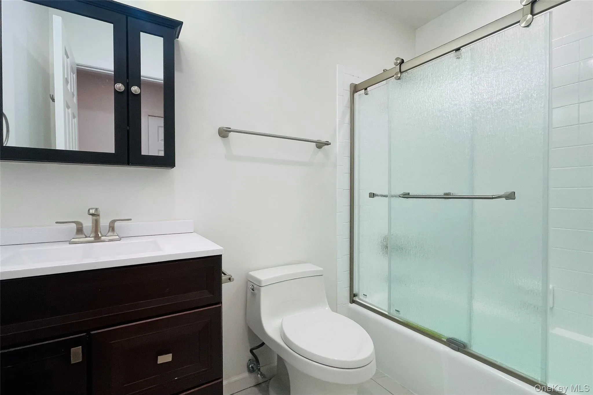 En suite bathroom with vanity and combined bath / shower with glass door En suite bathroom with vanity and combined bath / shower with glass door