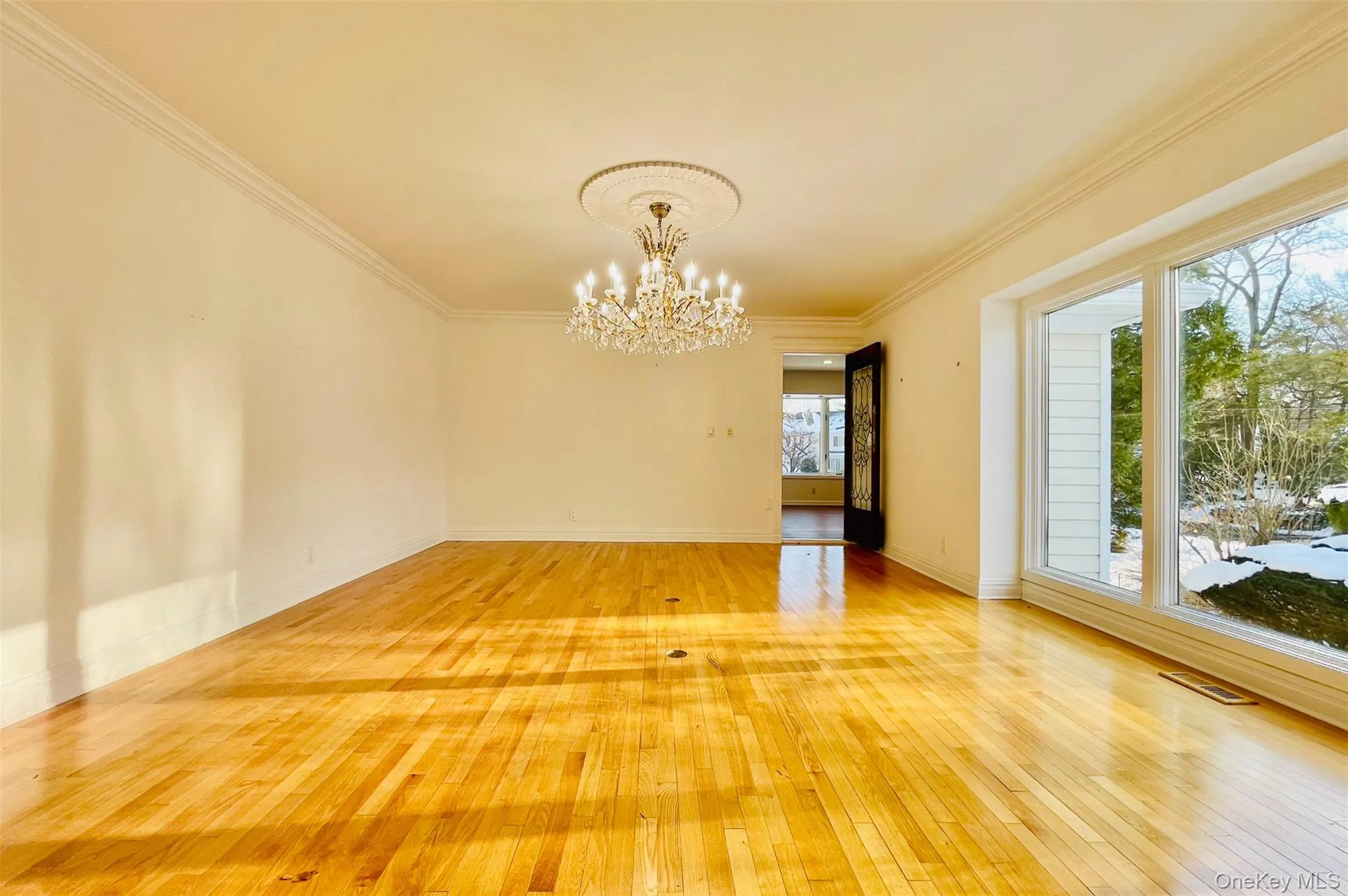 Unfurnished room featuring ornamental molding, hardwood / wood-style floors, and a chandelier Unfurnished room featuring ornamental molding, hardwood / wood-style floors, and a chandelier